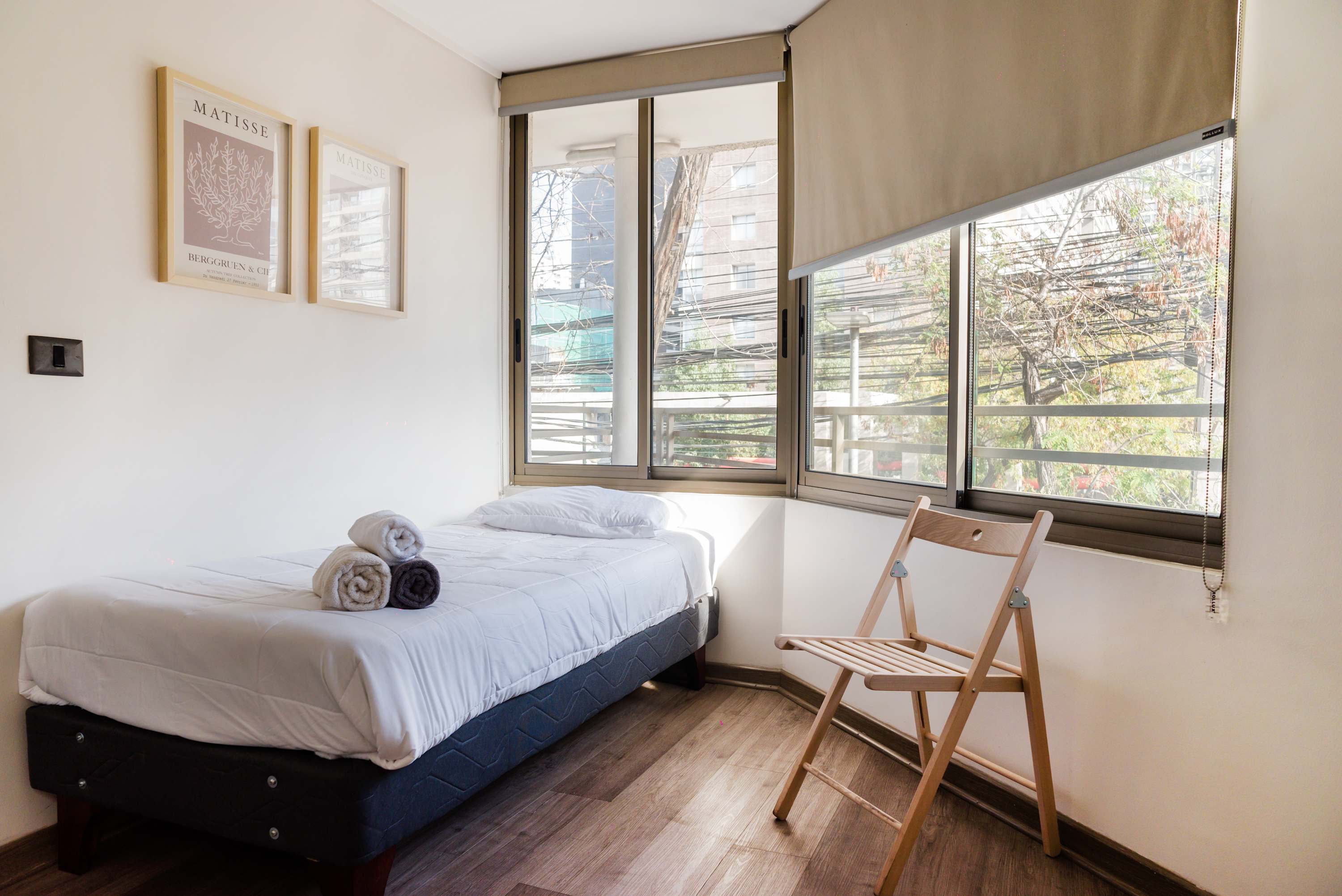 Cozy and bright bedroom with large windows and minimalist decor, perfect for a relaxing stay.