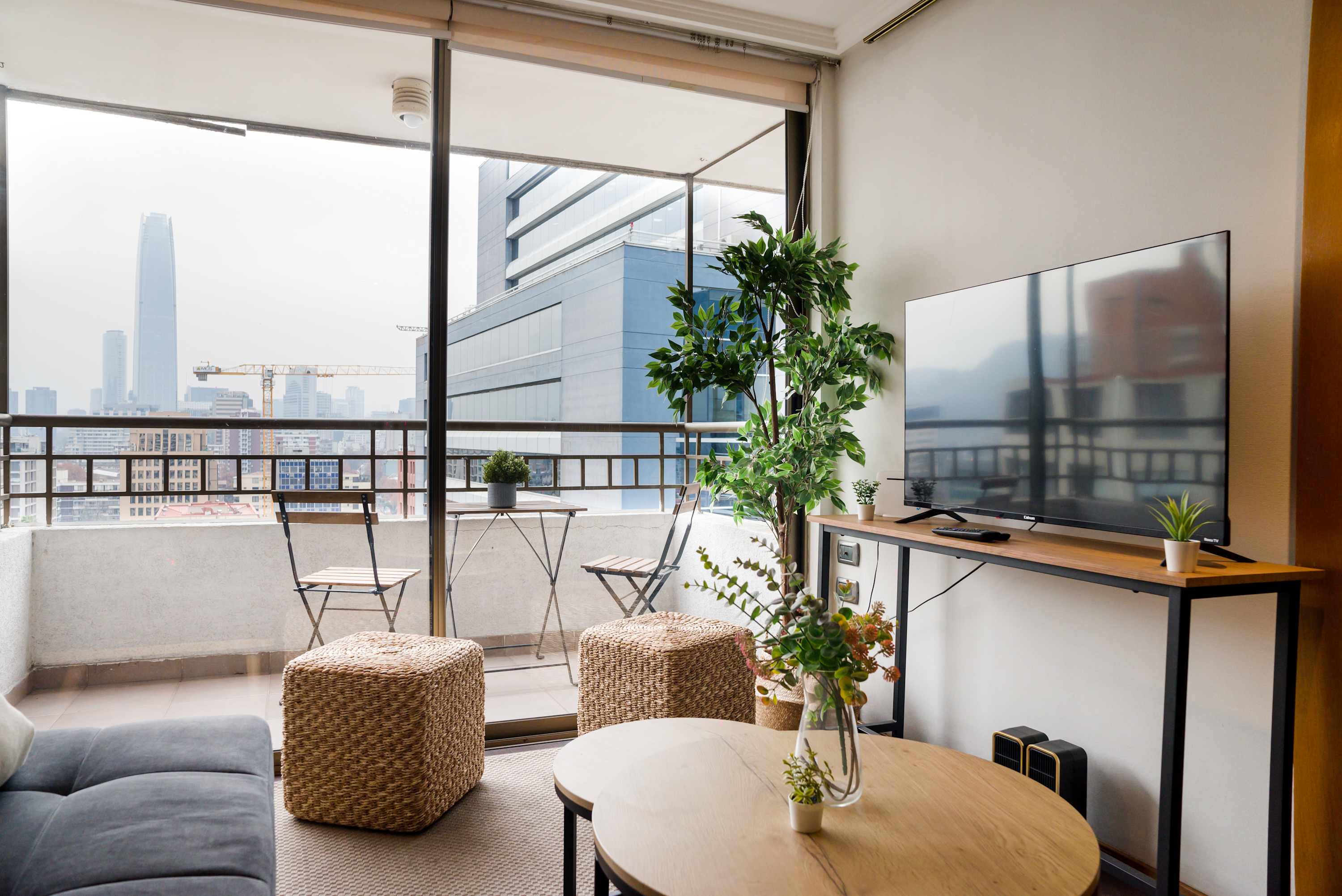 Enjoy stunning city views from this cozy living room with a private balcony, perfect for relaxing after a day of exploring Santiago.