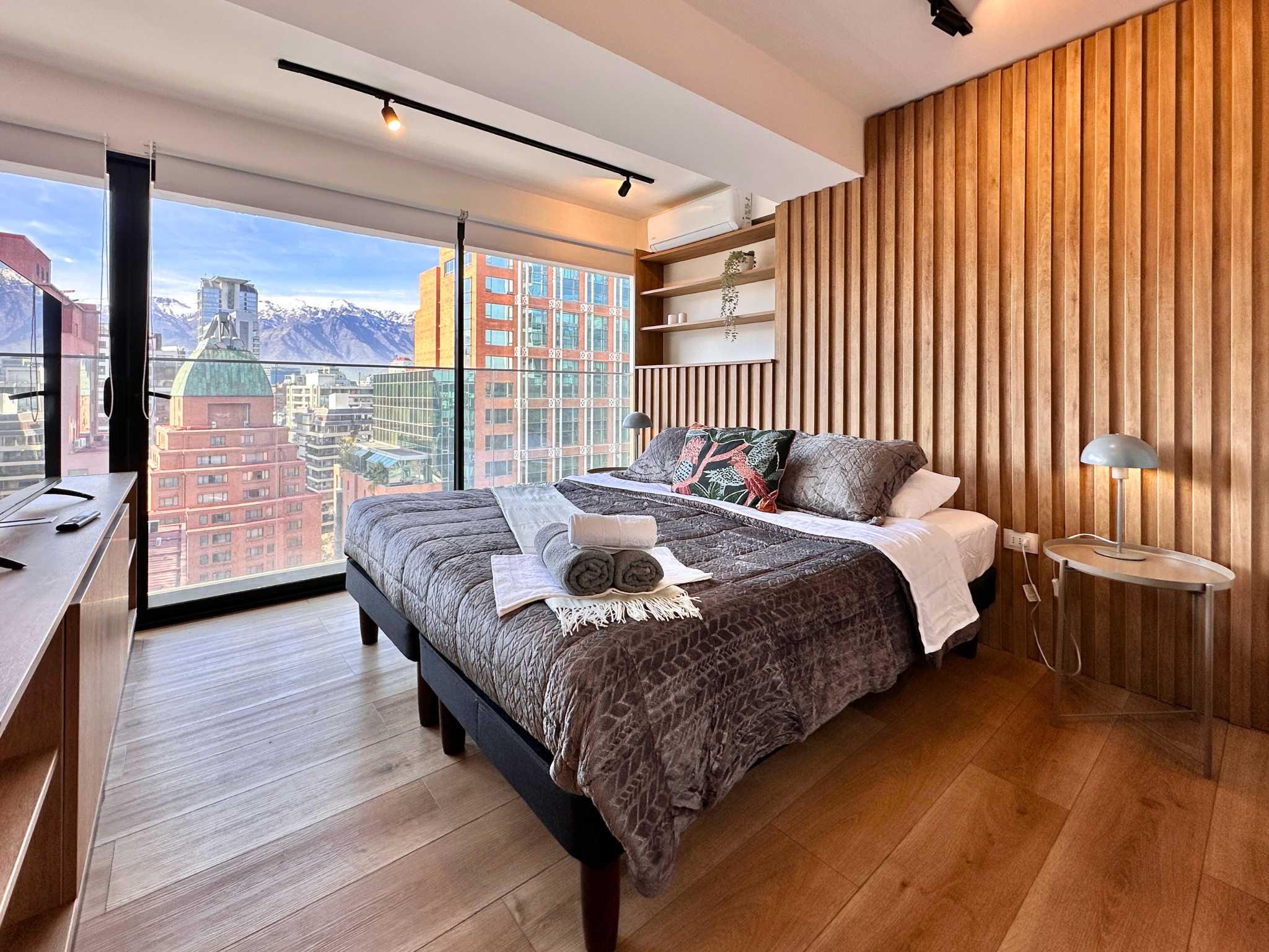 Experience breathtaking city and mountain views from this stylish studio, featuring a cozy bed and modern design elements.