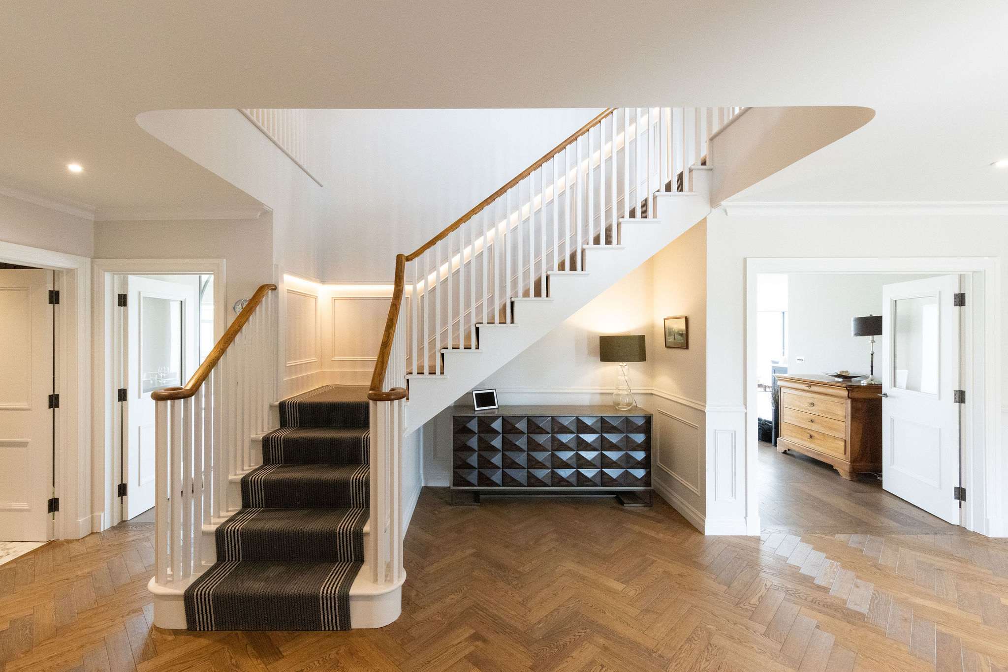Elegant hallway with feature staircase and parquet flooring