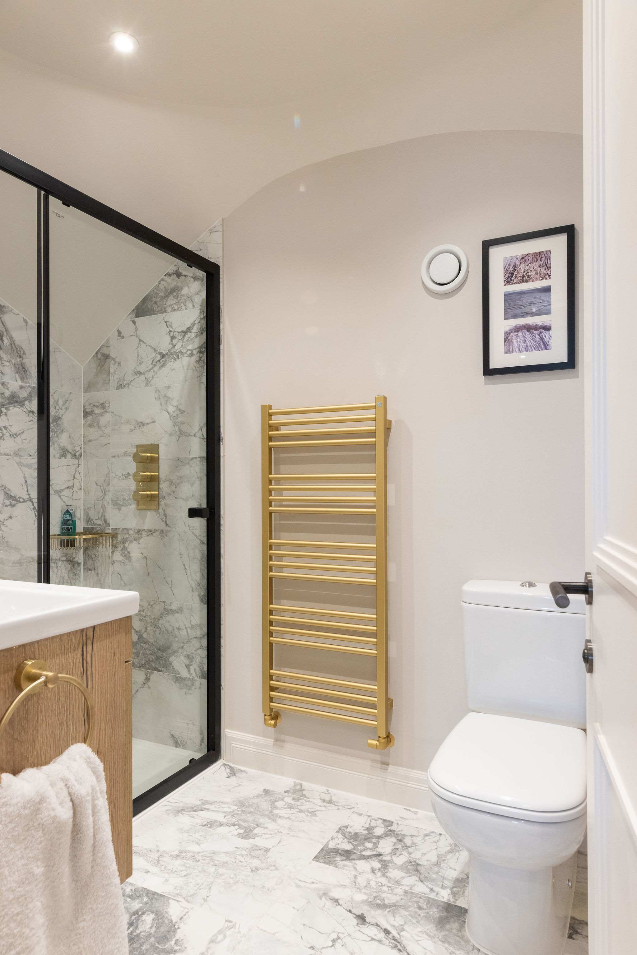 Elegant en suite with gold towel rail and marble tiles