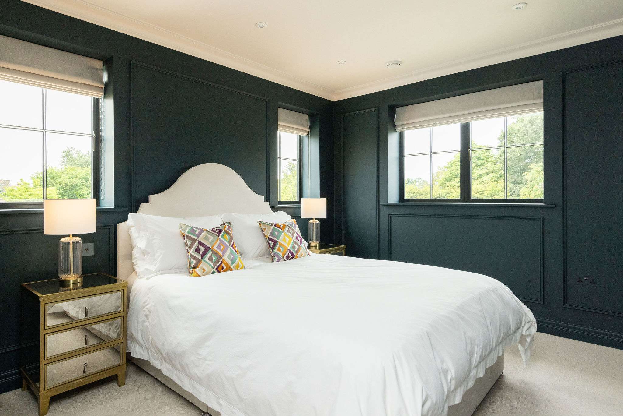 Striking king bedroom with bold dark walls and triple aspect windows
