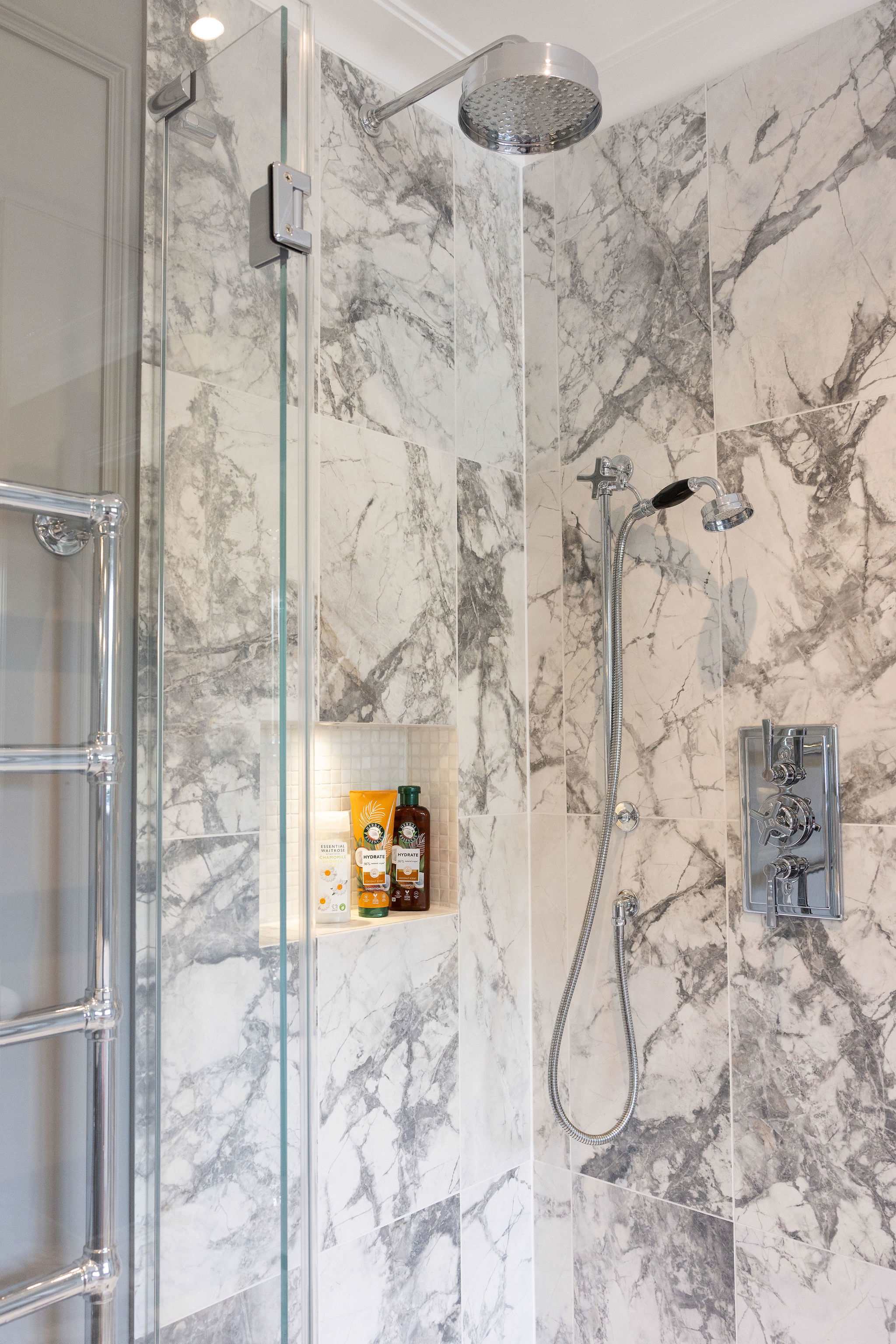 Marble-tiled rainfall shower with luxe fixtures