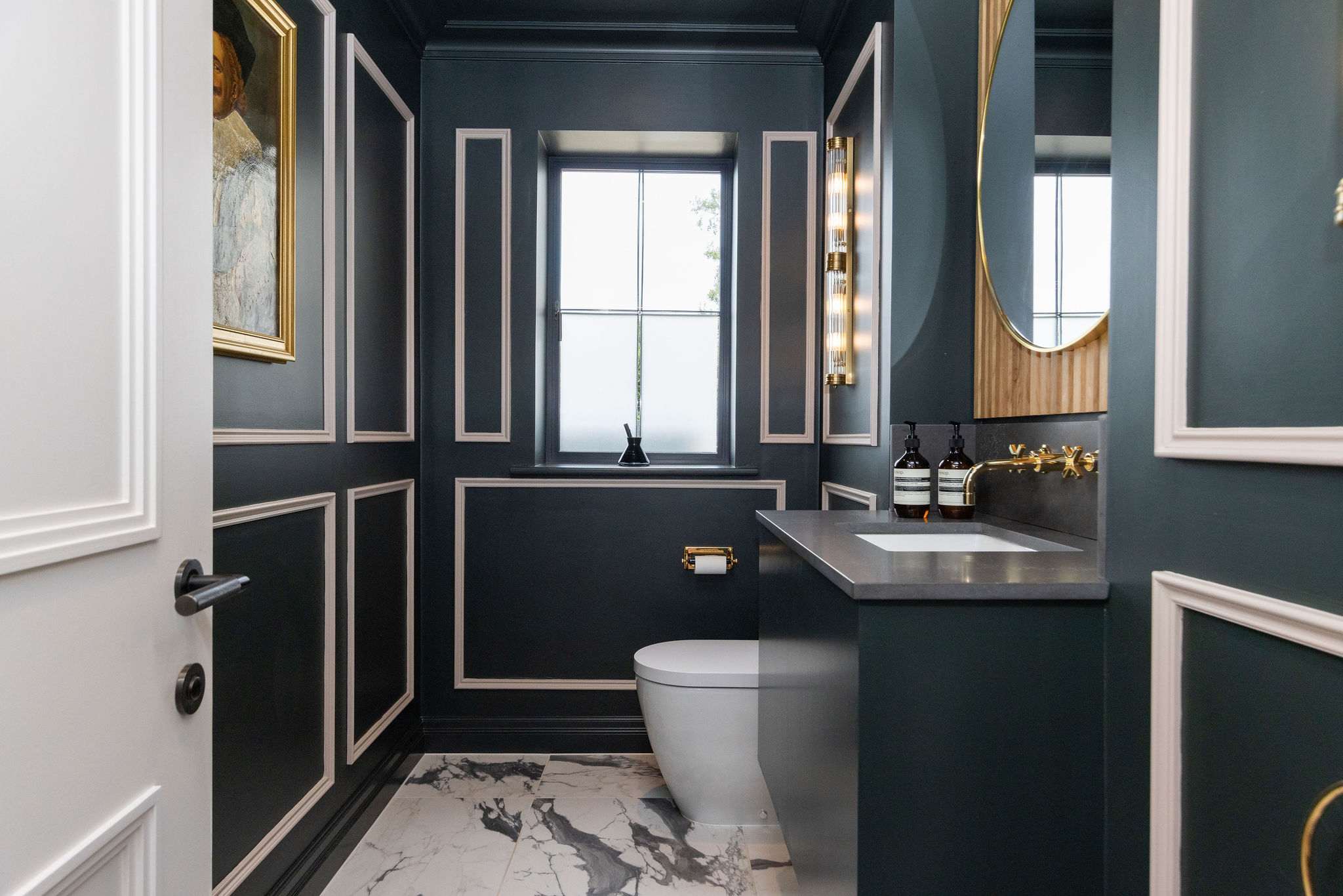 A luxurious ground floor cloakroom with panelled walls, marble flooring, and gold accents