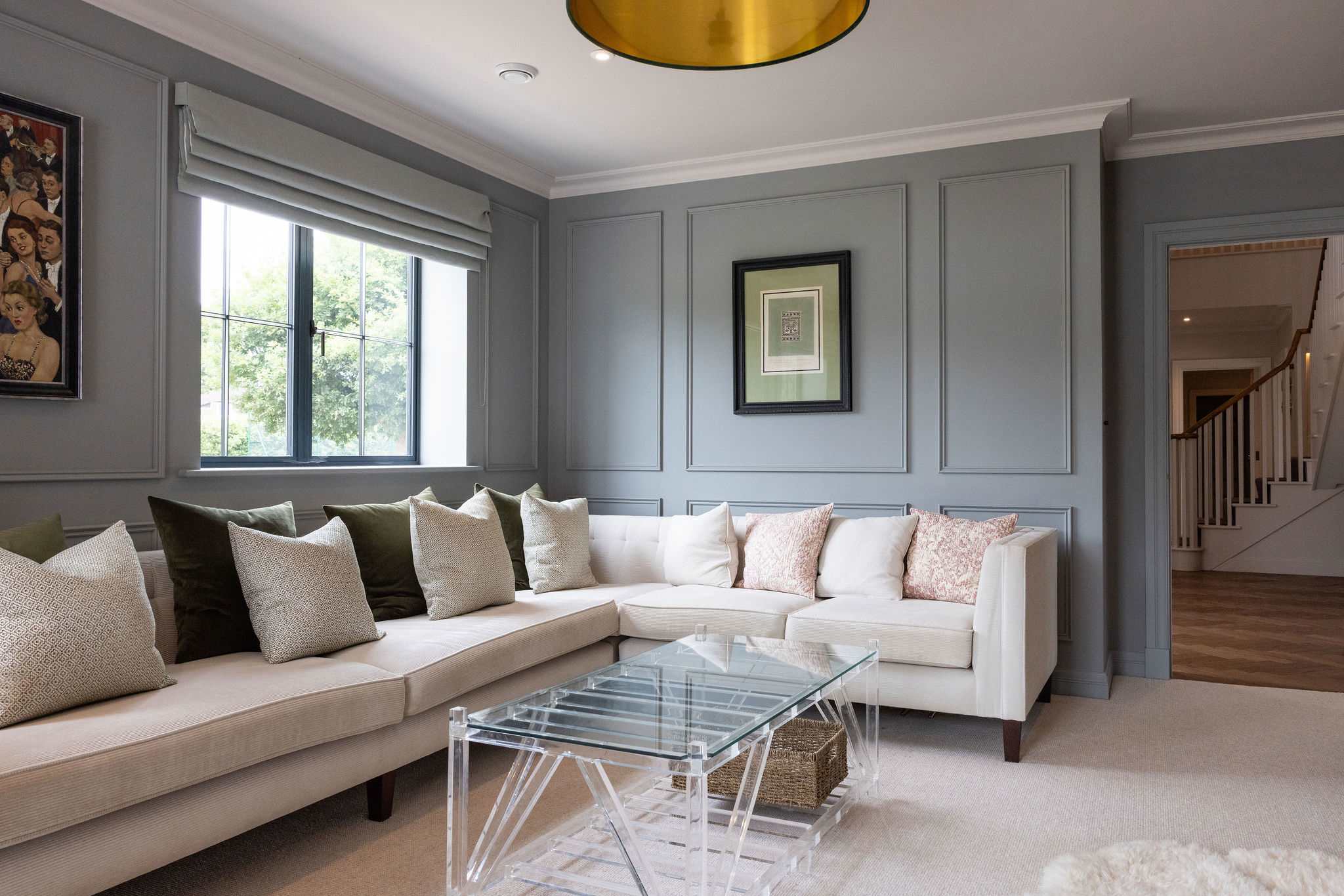 A stylish living area with a large corner sofa, statement lighting, and a calming colour palette