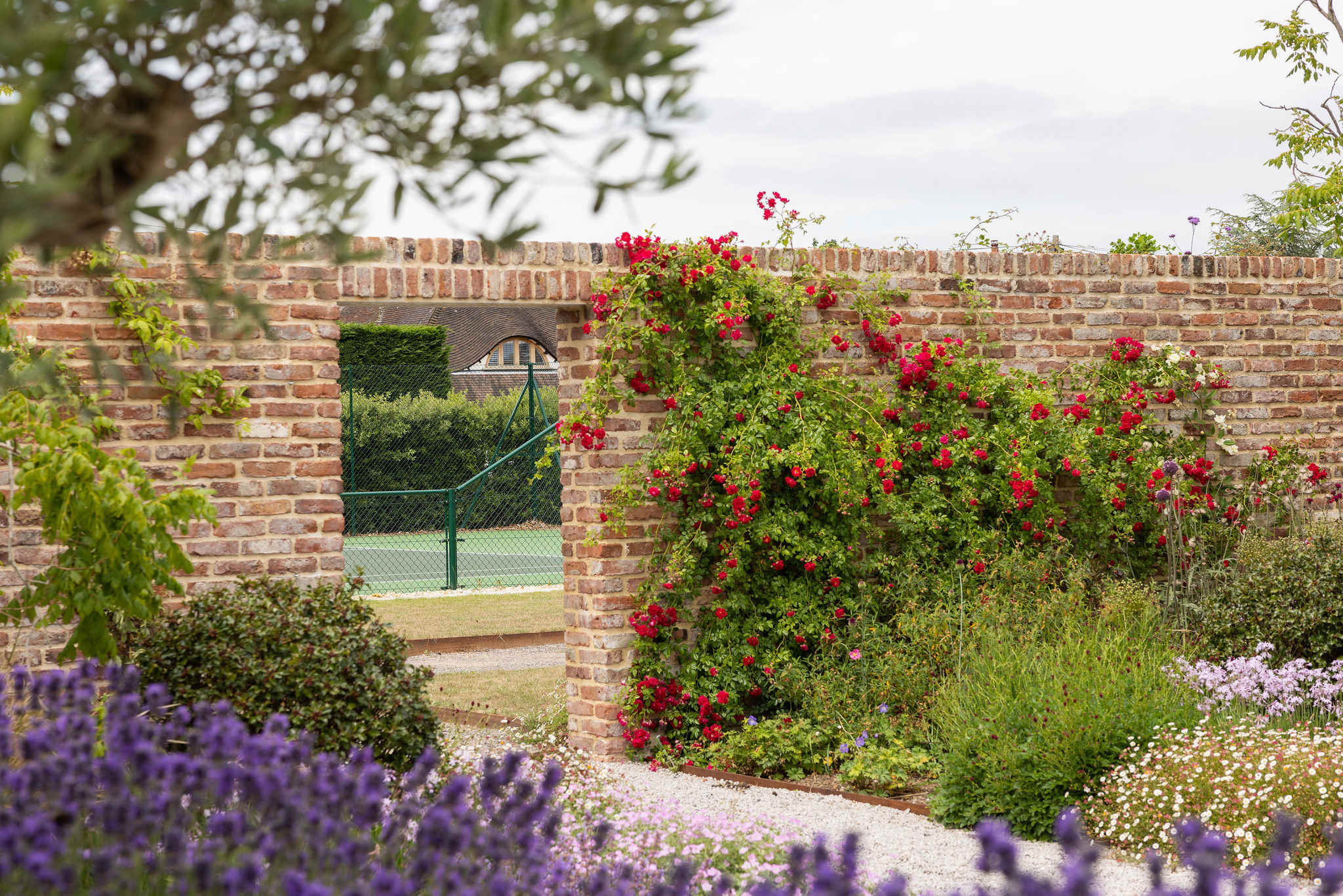 Walled garden with vibrant flowers and tennis court access