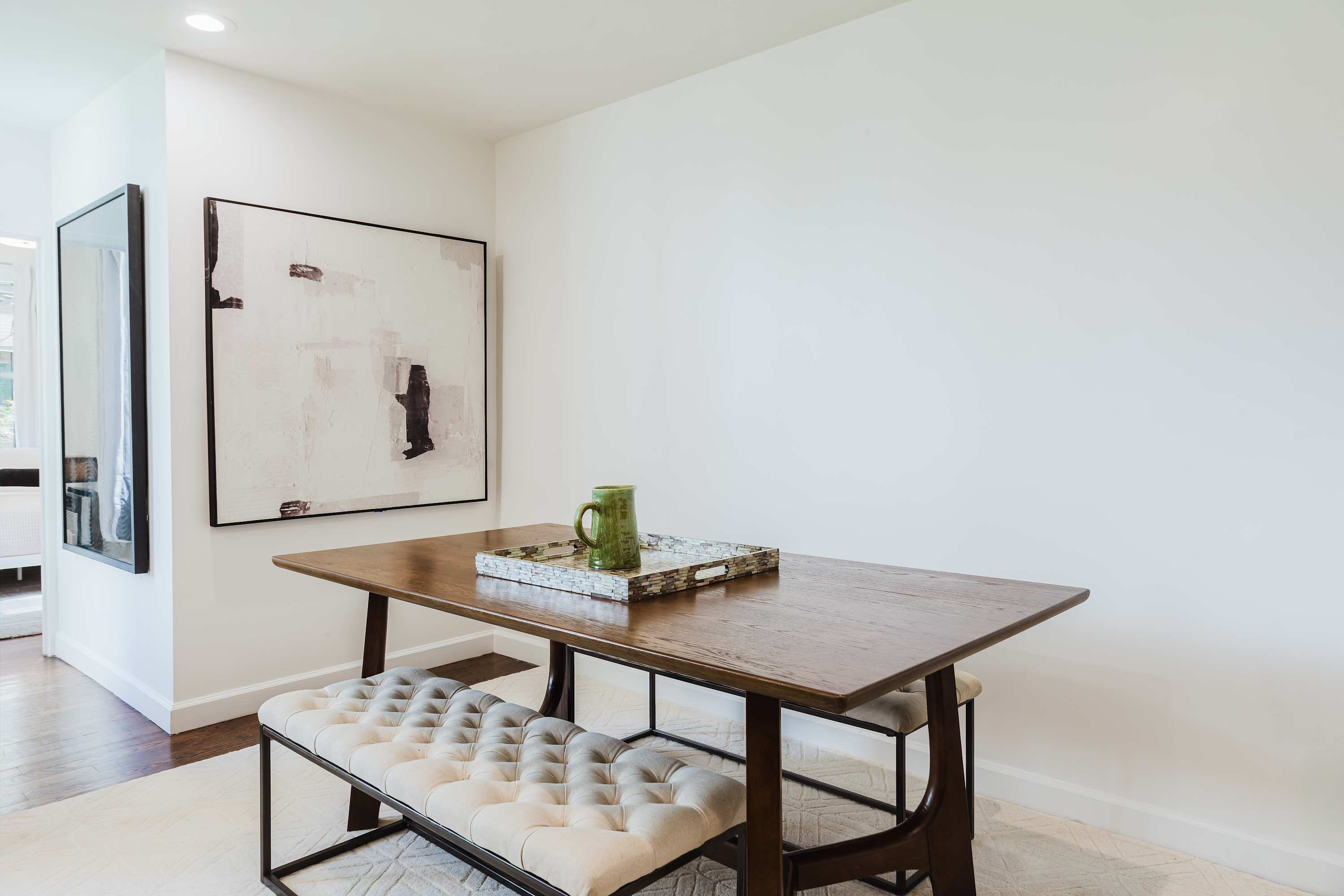 Dining nook with a wood table, tufted bench, and abstract artwork.