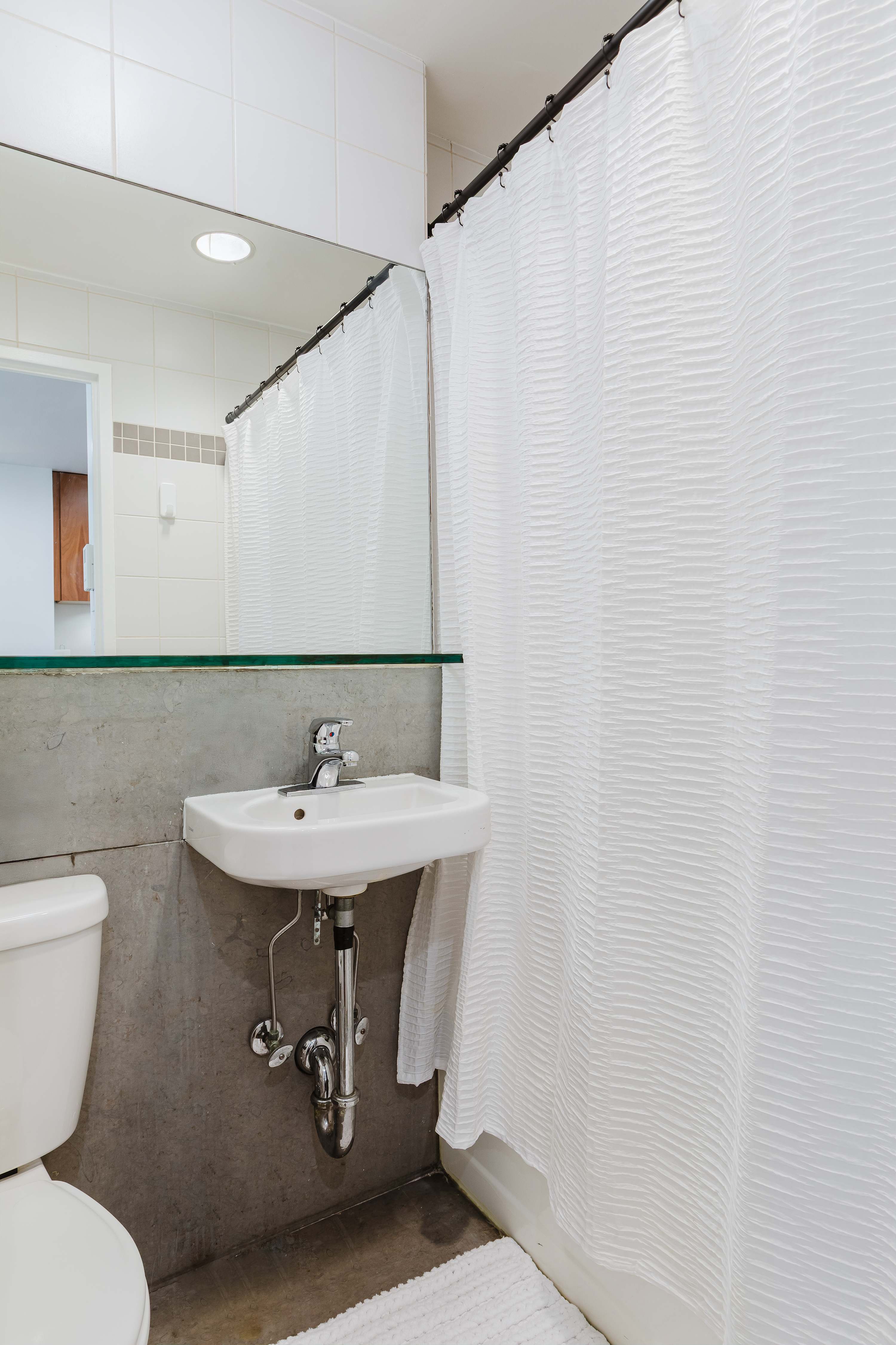 Bathroom with a pedestal sink, glass shelf, and shower-tub combo.