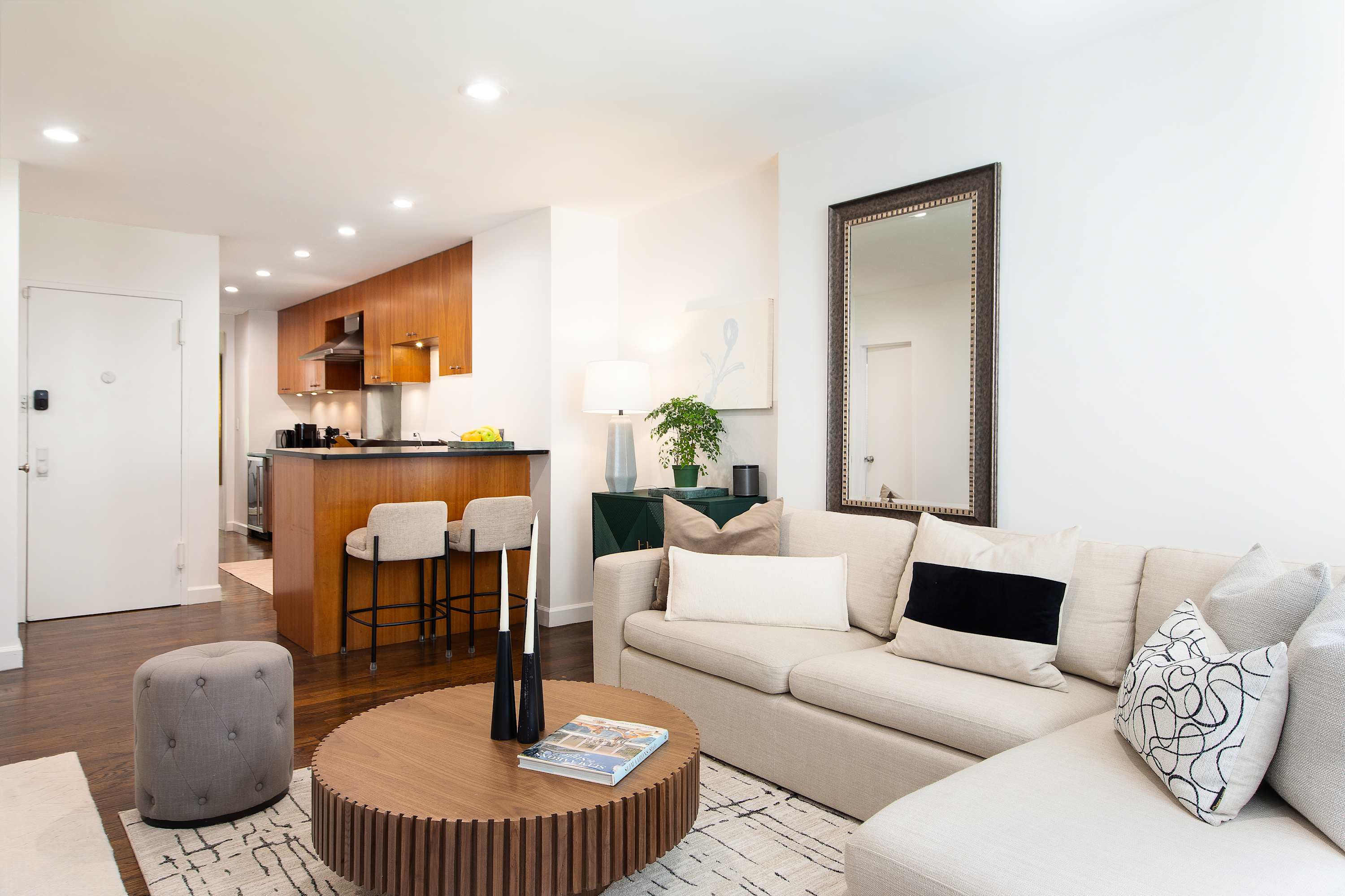 Open living area with a cream sofa, wood coffee table, and a view through to the wood-cabinet kitchen.