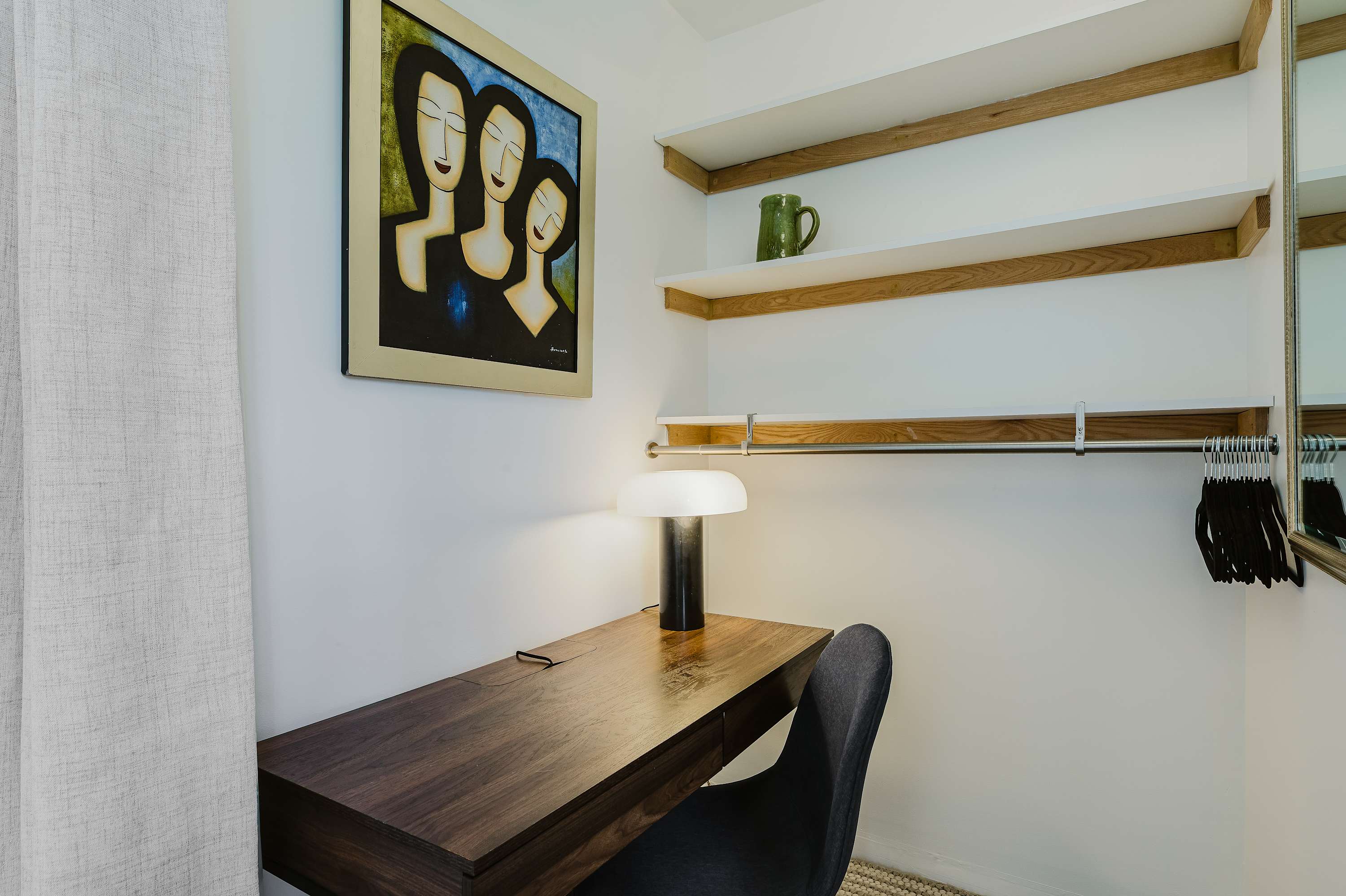 Closet and study nook with a wood desk, task lamp, open shelving, and a hanging rod.