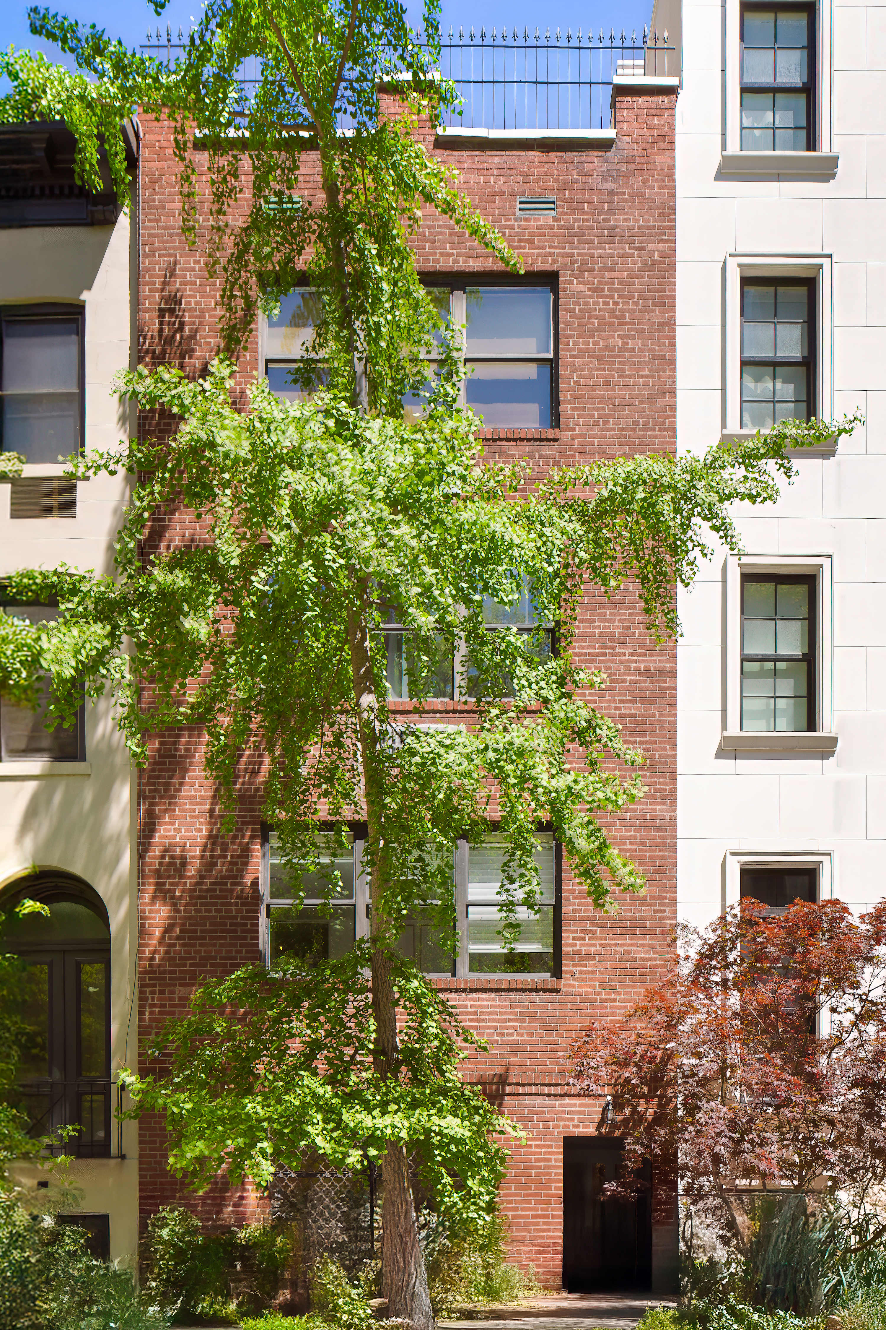Exterior view of the brick townhouse facade framed by a street tree.