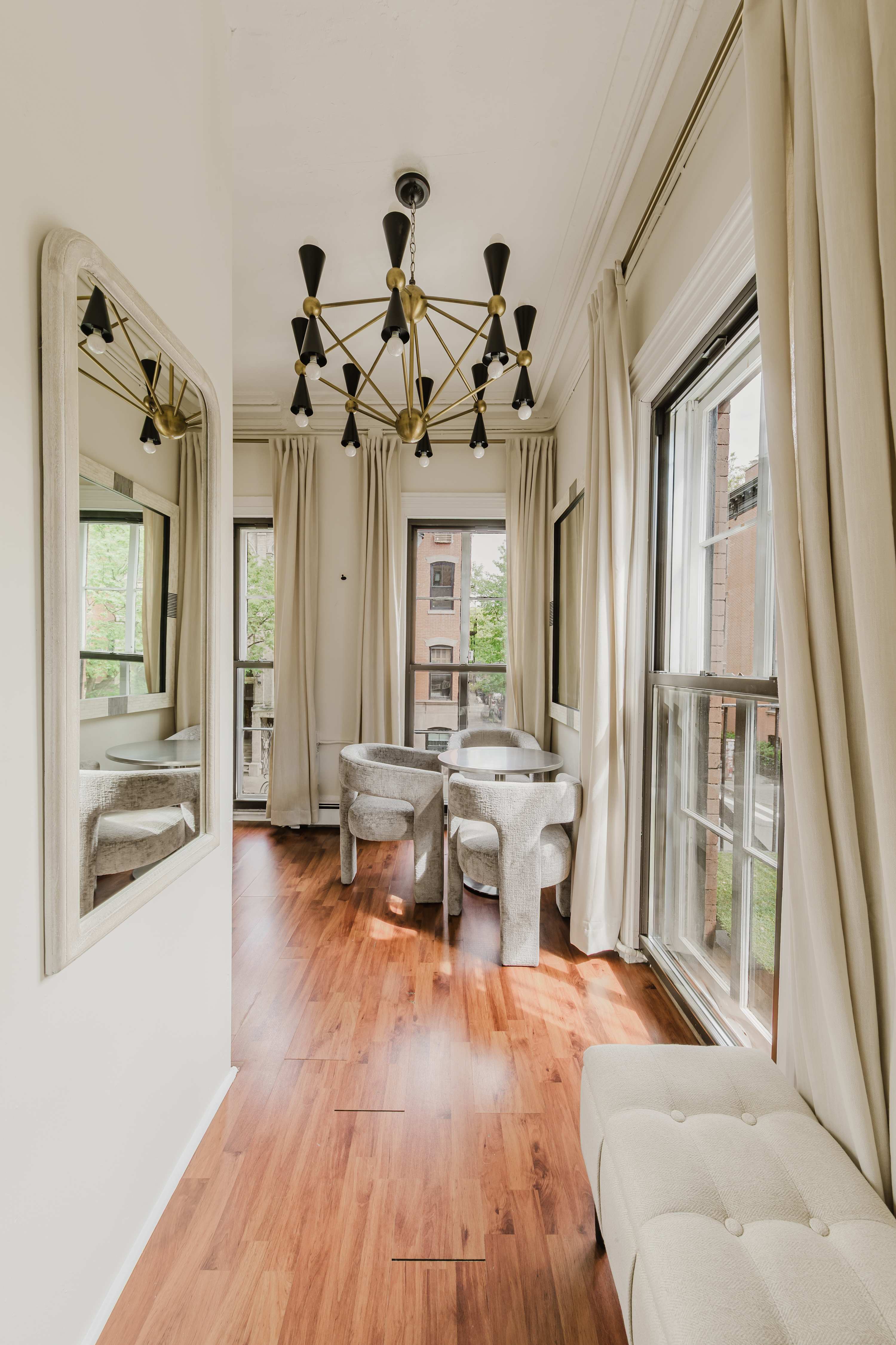 Hallway view toward the dining area, with a brass sputnik chandelier, tall windows, and a runner over wood floors.