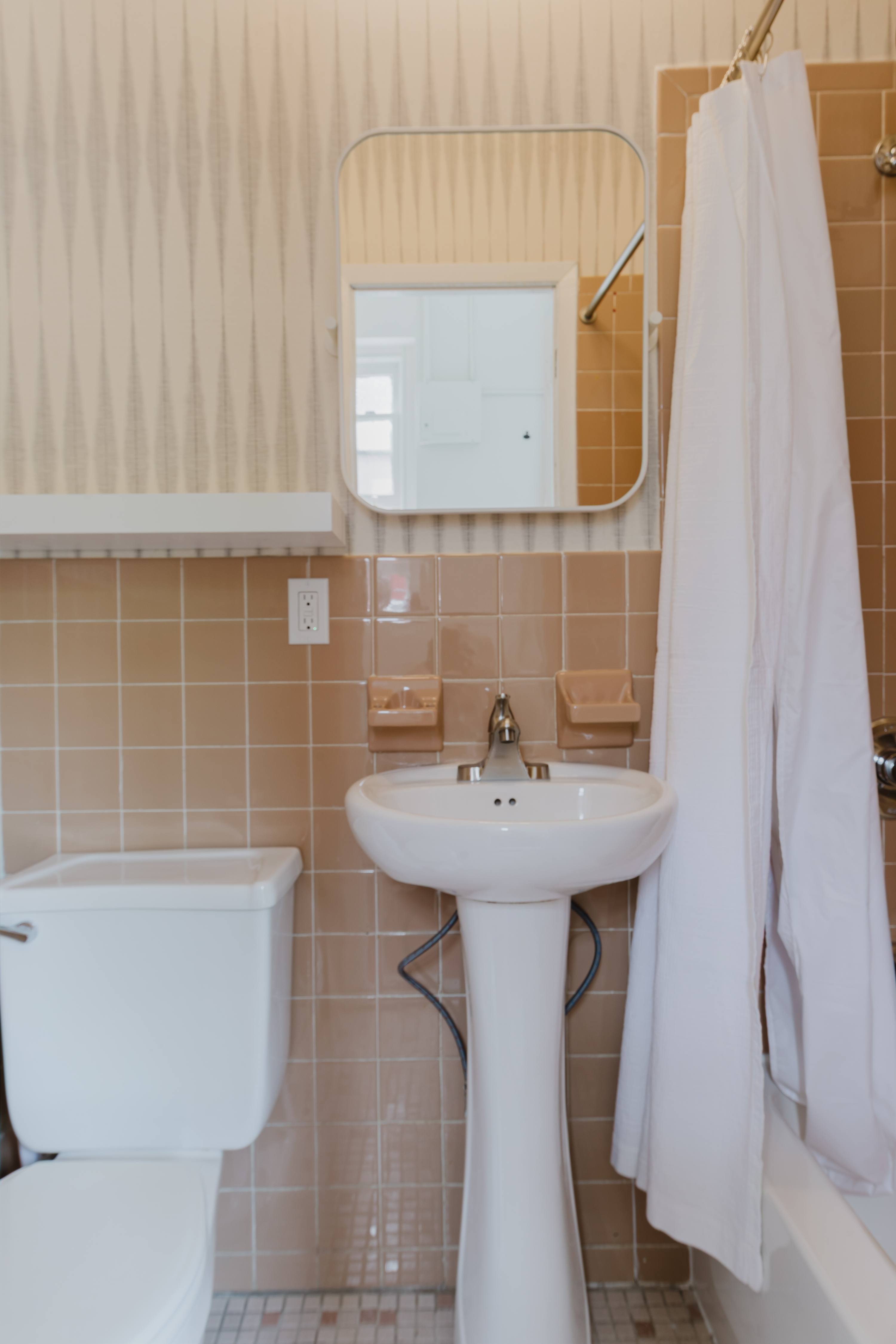 Bathroom with a pedestal sink, mirrored medicine cabinet, and tiled walls.