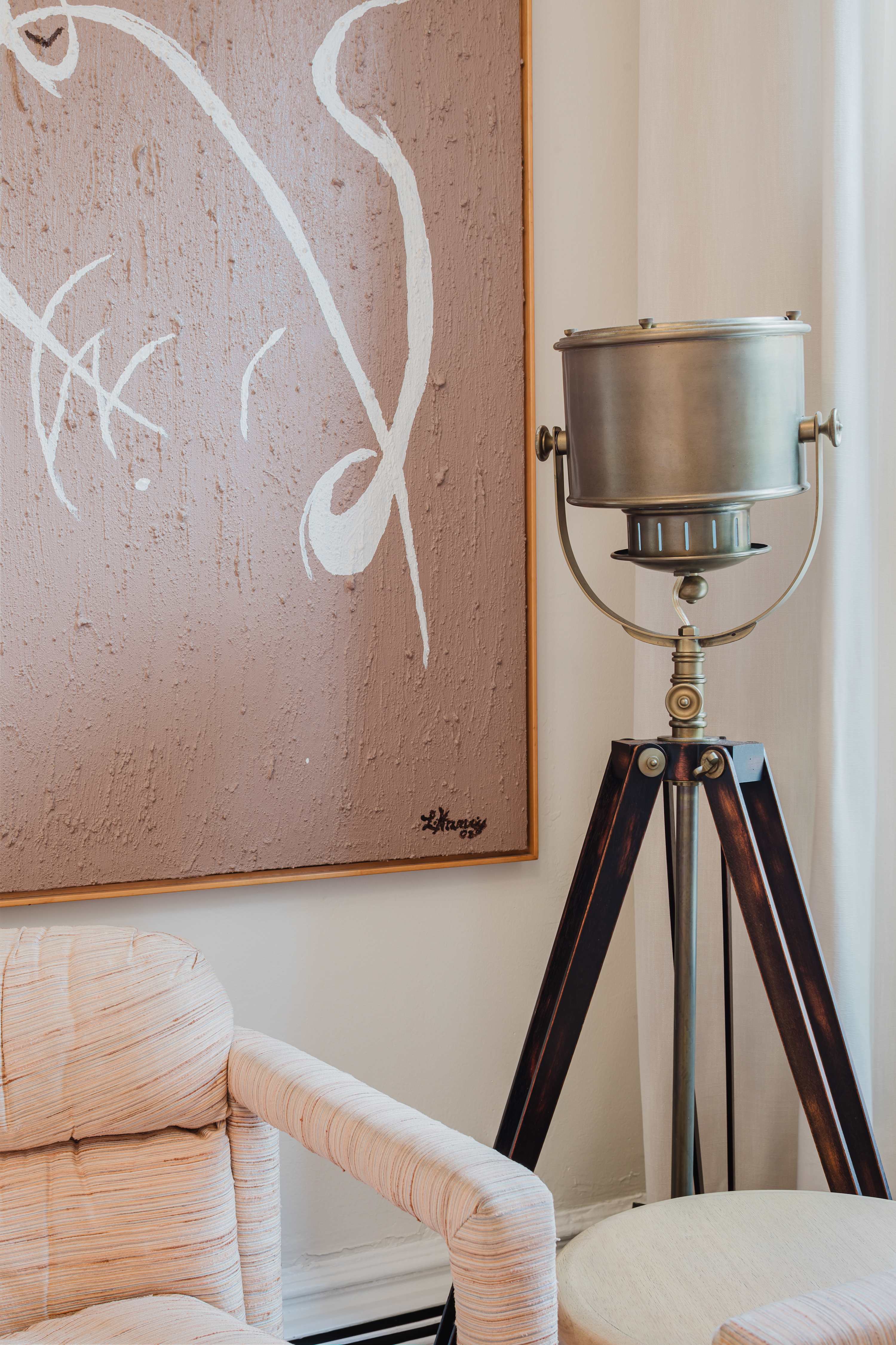 Close-up of the abstract pink artwork above a vintage industrial floor lamp and upholstered armchair.