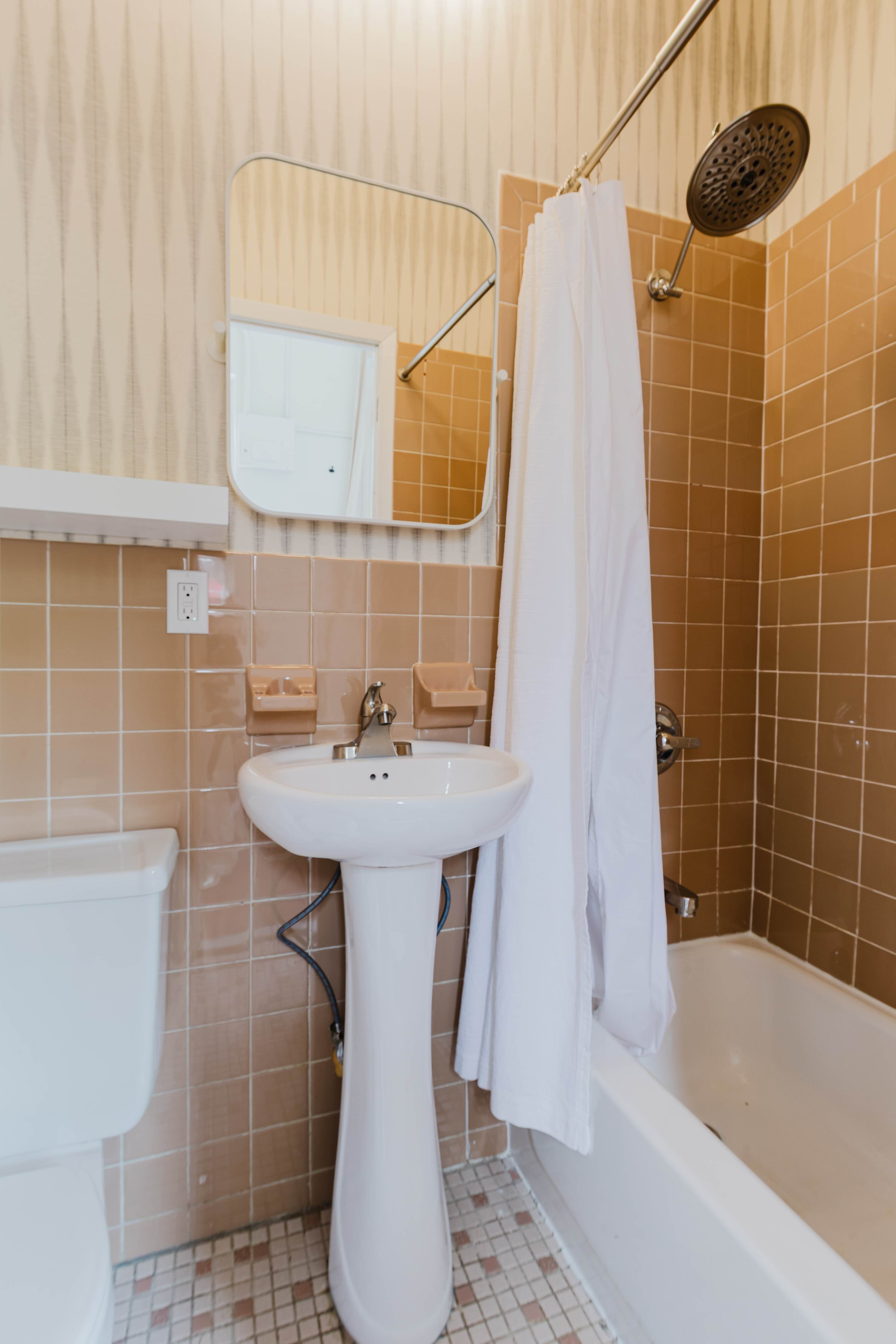 Bathroom with a pedestal sink, tiled tub and shower, and mirrored medicine cabinet.