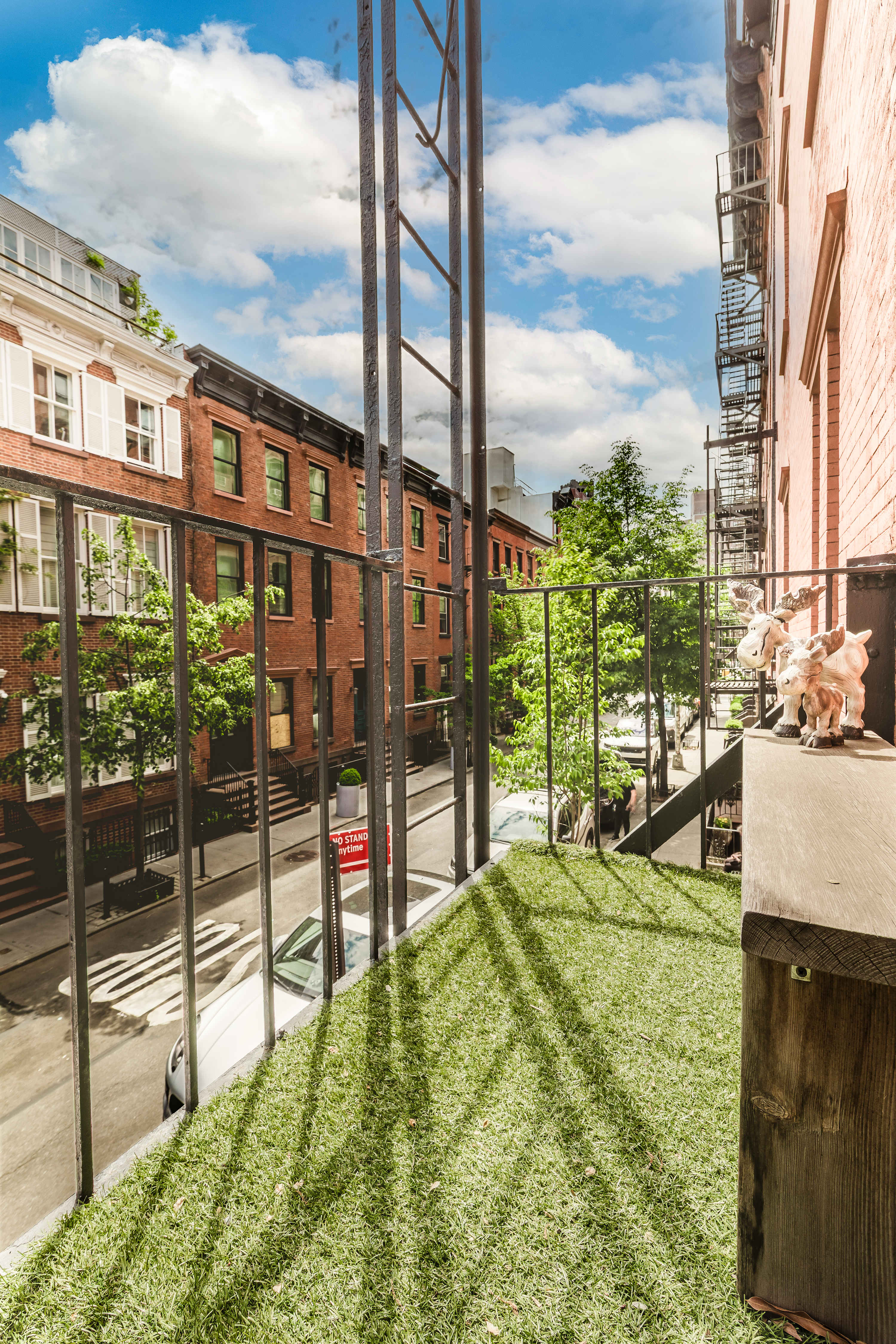 View along a fire escape railing over a tree-lined courtyard below.