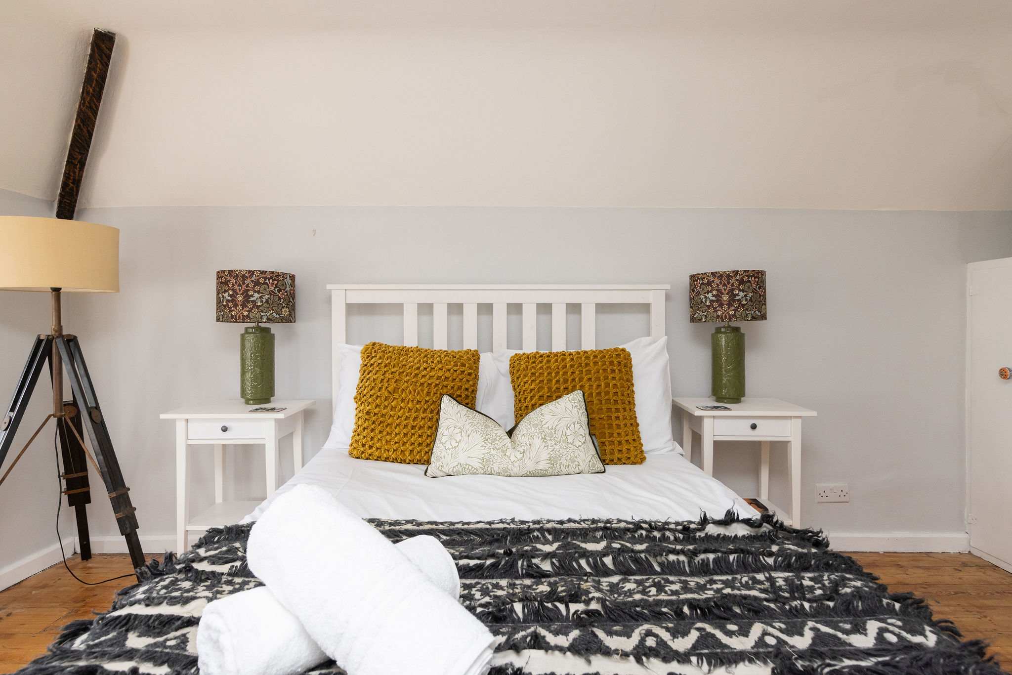 The master bedroom has a double bed with bedside tables and lamps.