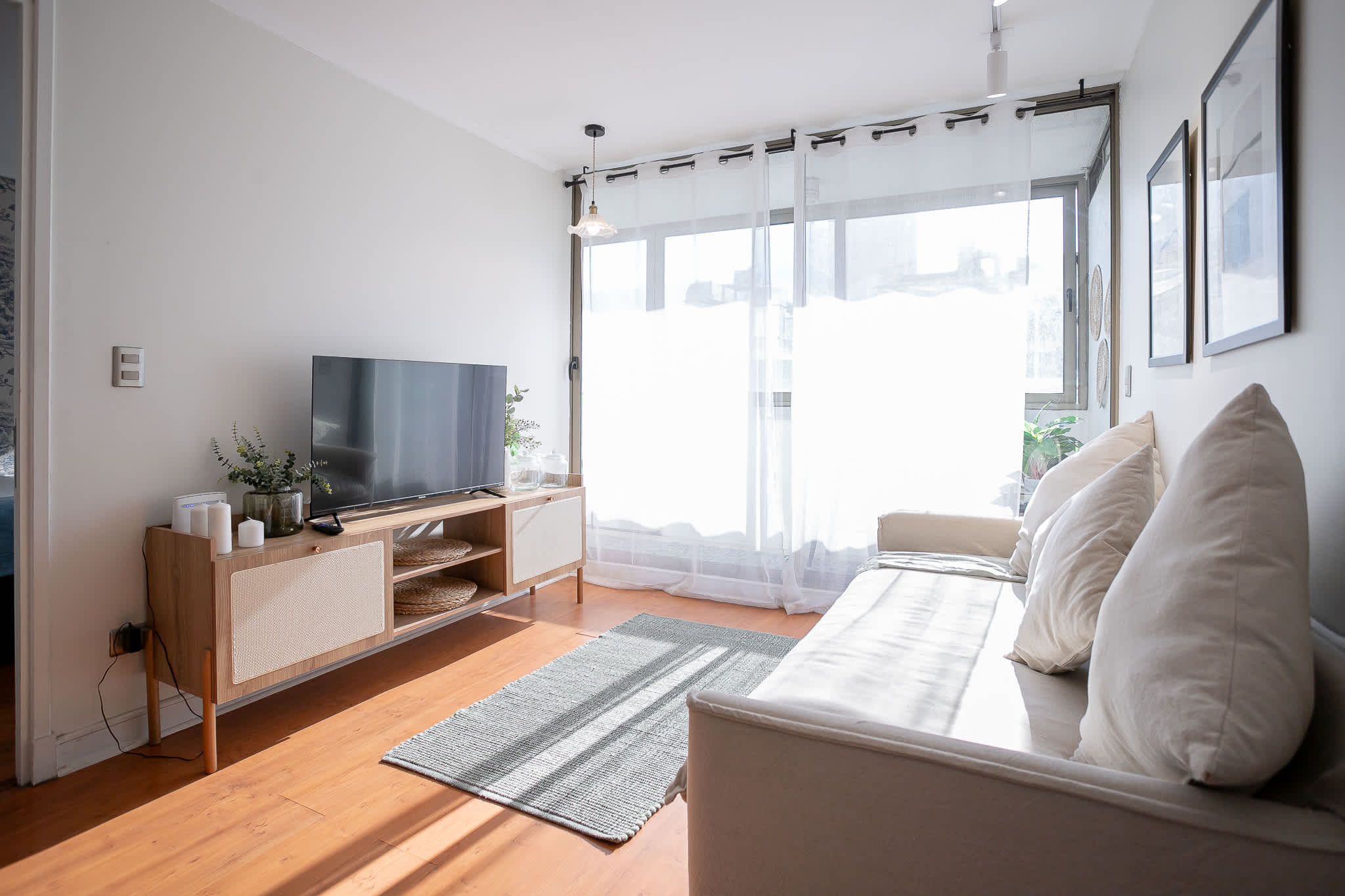 Relax in this sunlit living room with modern decor and a cozy sofa, perfect for unwinding after a day of exploring.