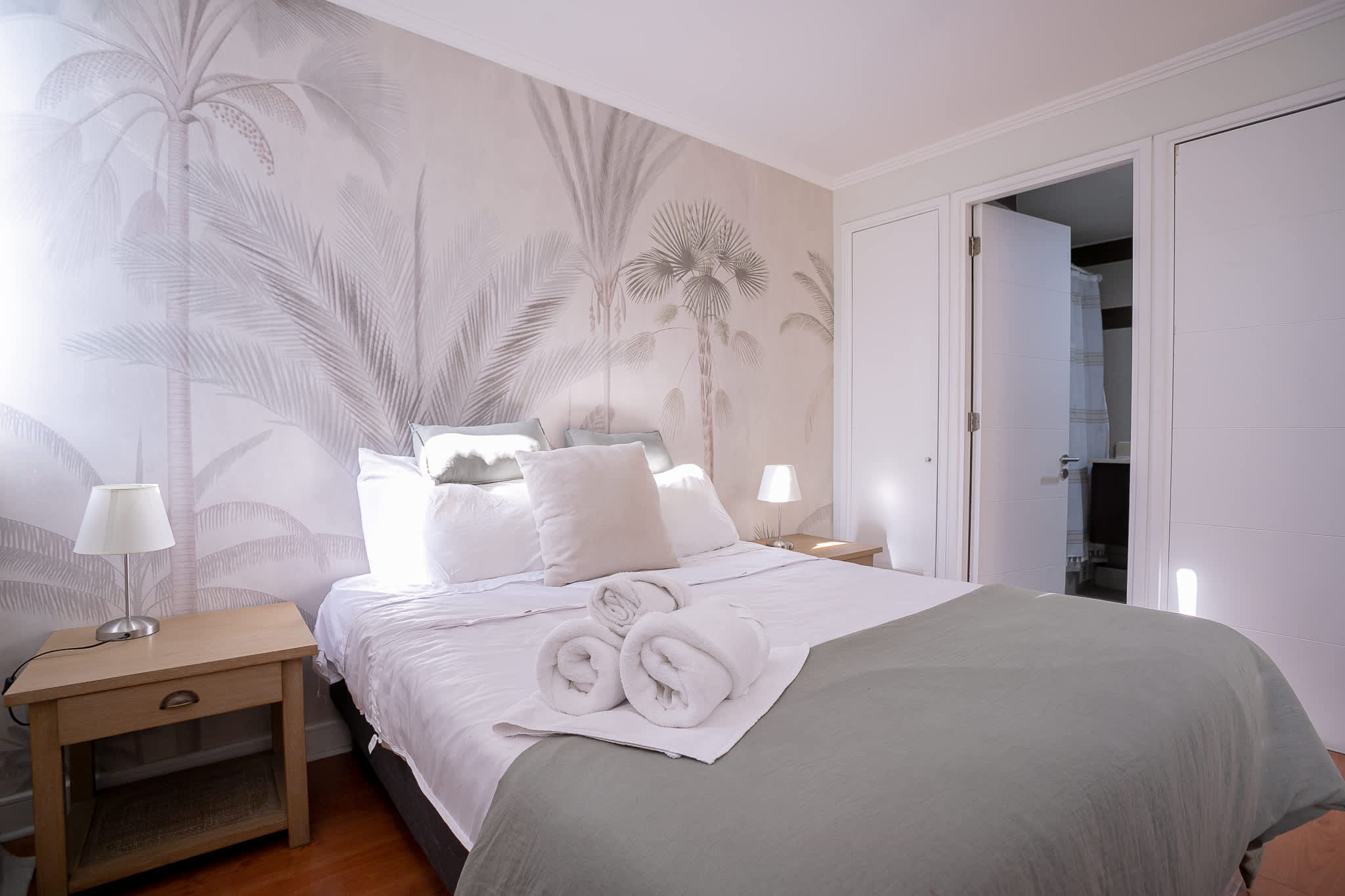 Relax in this cozy bedroom with tropical vibes and plush bedding, perfect for a restful night's sleep.