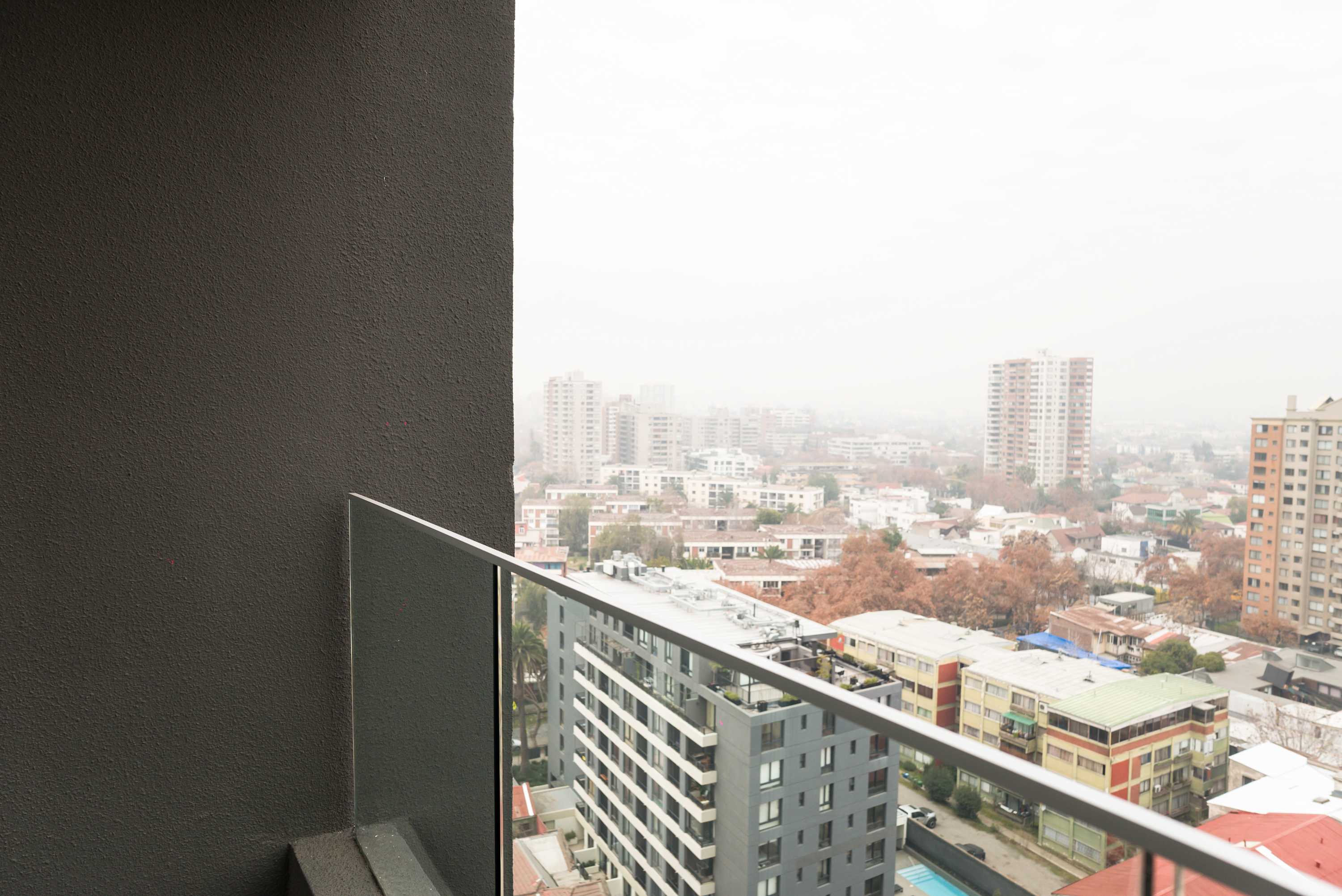 Private balcony with a glass railing and sweeping views over the city skyline and surrounding rooftops.