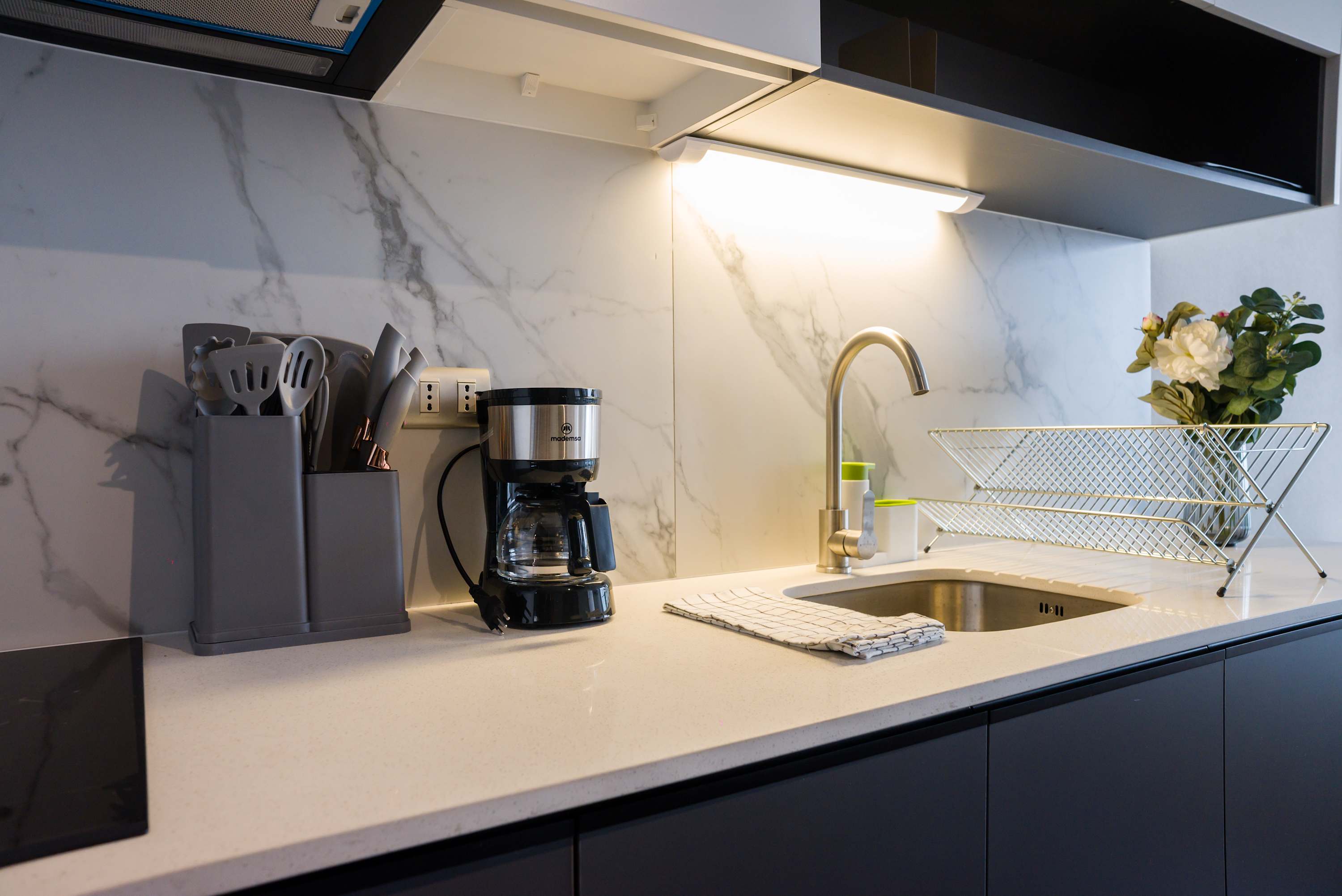 Modern private kitchen with marble-look backsplash, generous counter space, coffee maker, and a convenient sink with dish rack.