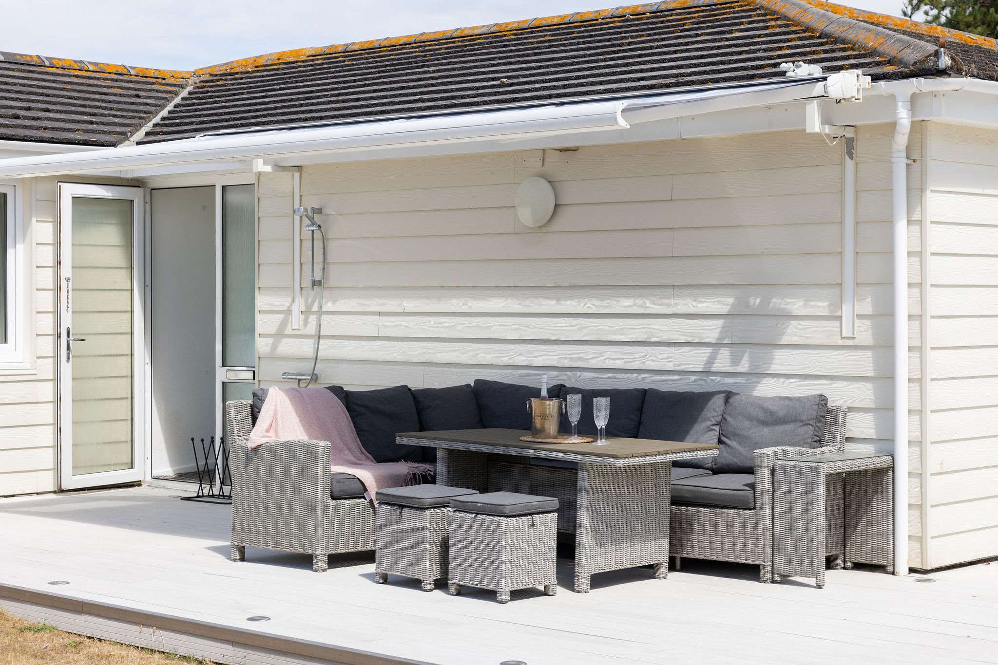 Comfy corner seating with a table and outdoor shower—perfect after the beach