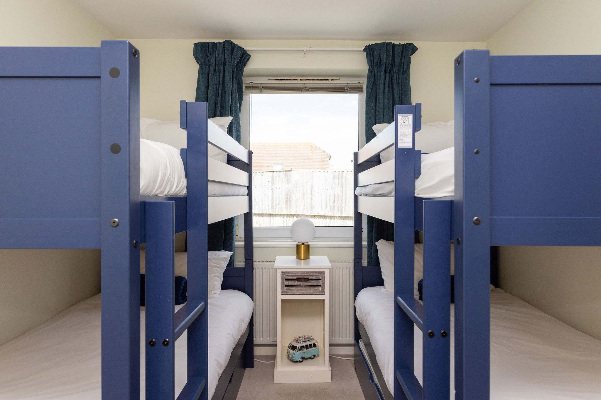 Kids' bunk room with four beds and playful decor