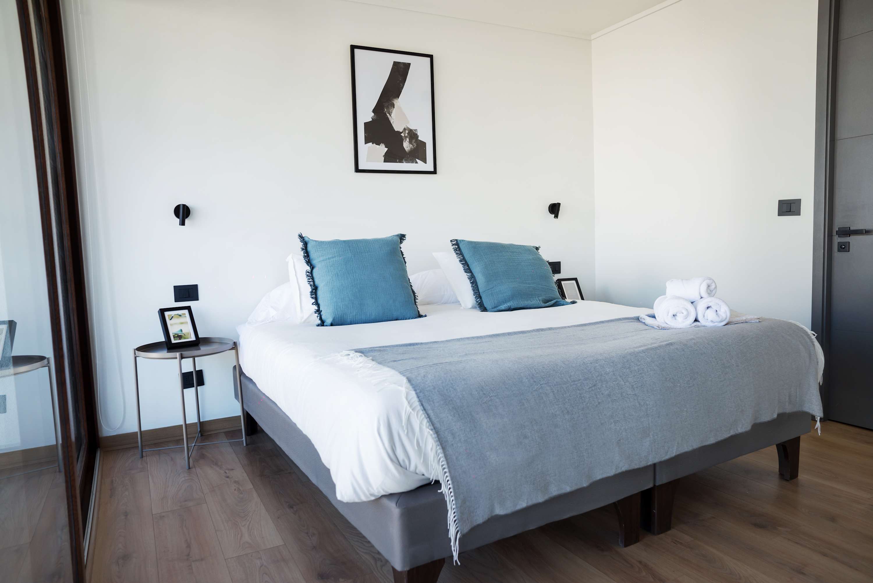 Relax in this serene bedroom with cozy linens and stylish decor, perfect for a restful stay.