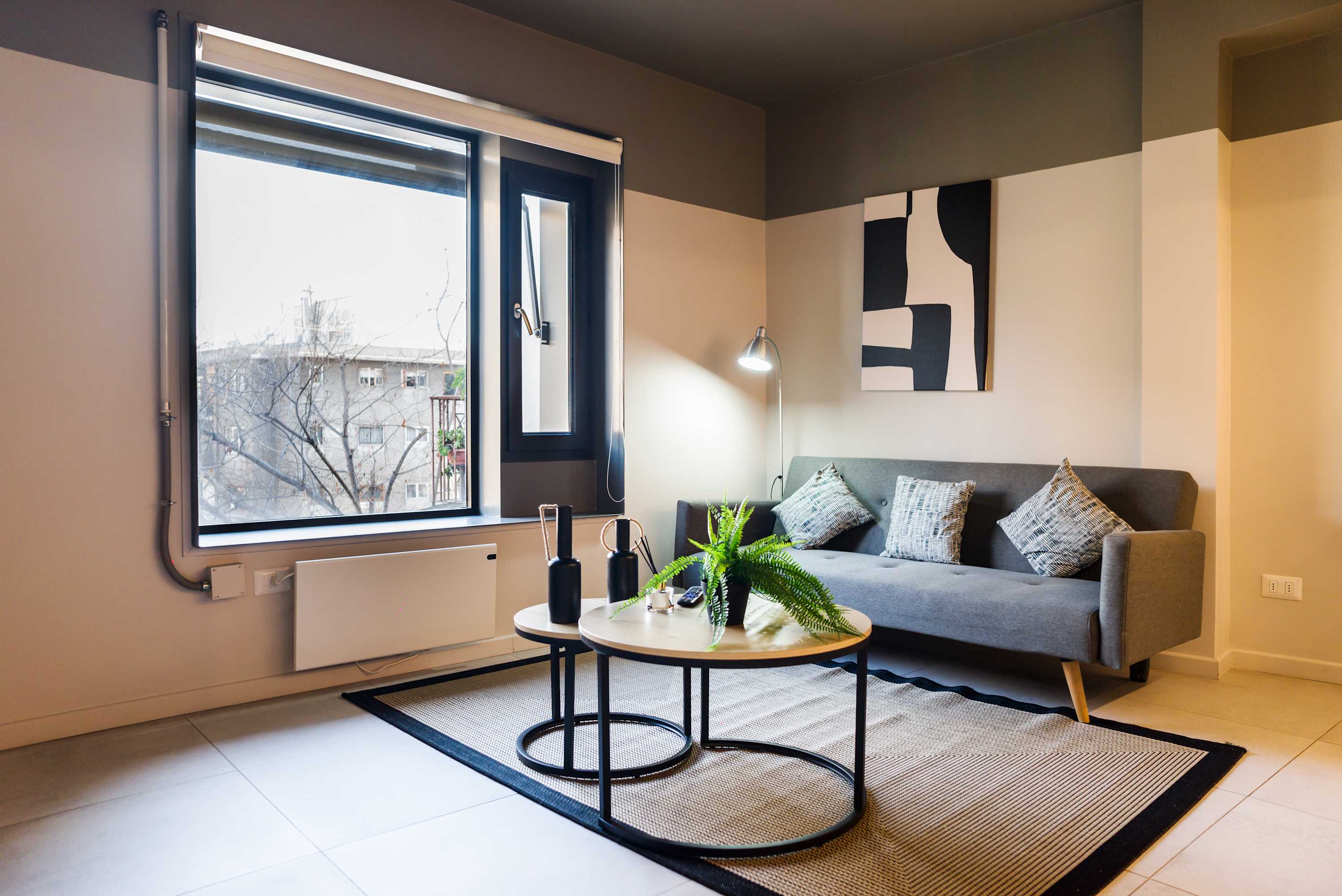 Relax in this stylish living room with ample natural light and modern decor, perfect for unwinding after a day exploring the city.