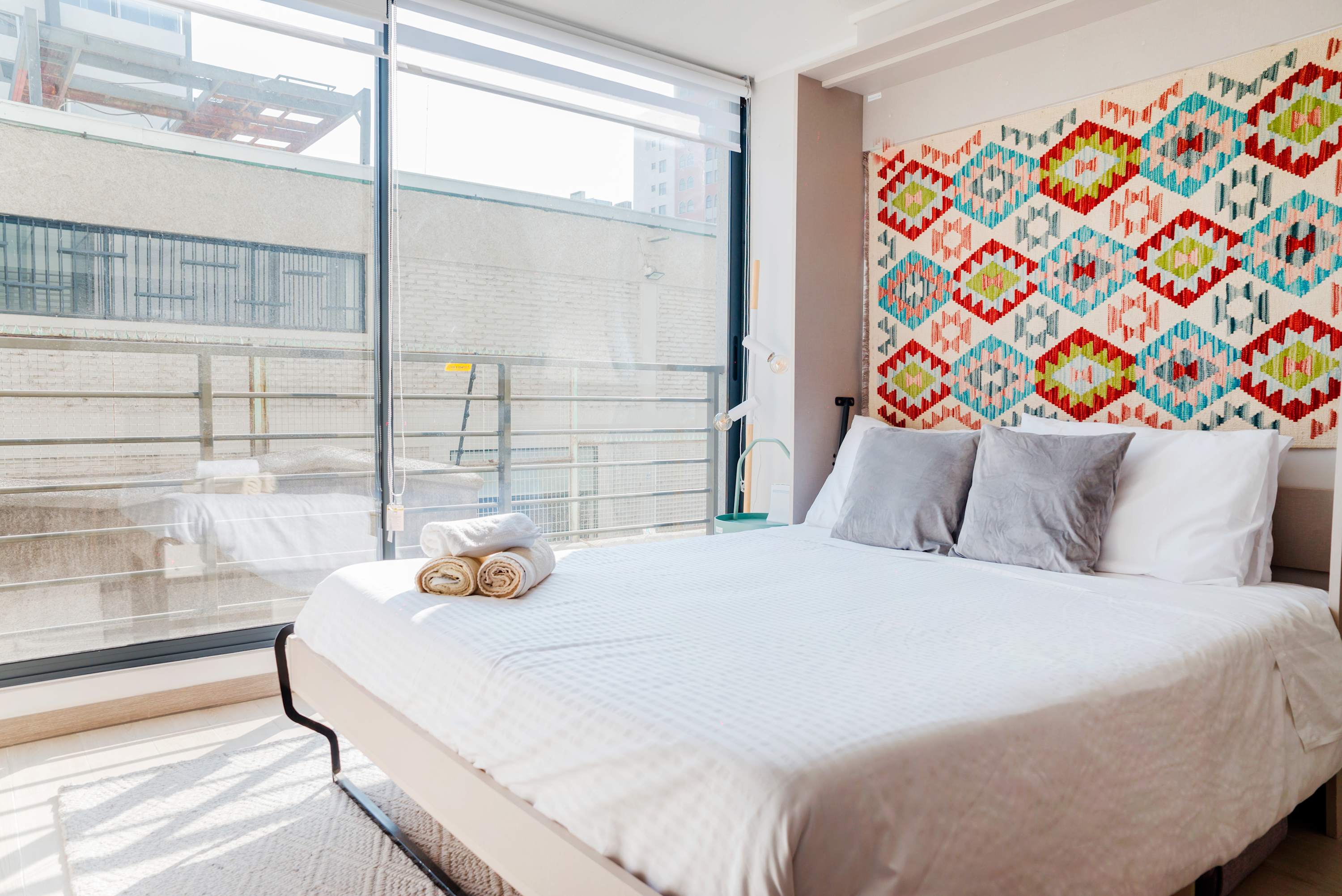 Cozy studio with vibrant tapestry and abundant natural light, perfect for a relaxing stay in the heart of the city.