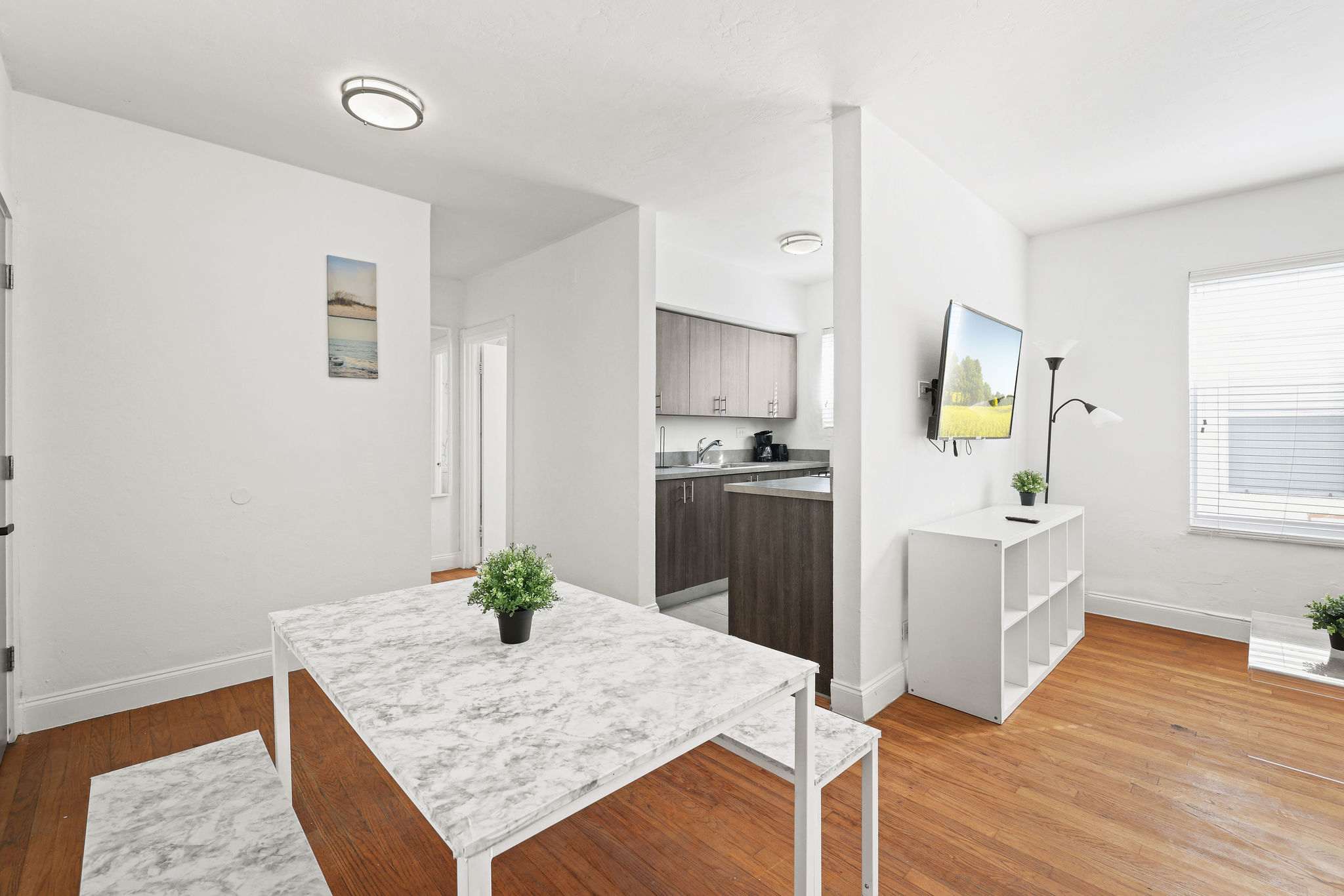 Cozy dining area with modern marble-patterned table, perfect for meals or work. Enjoy natural light and a convenient kitchen setup.