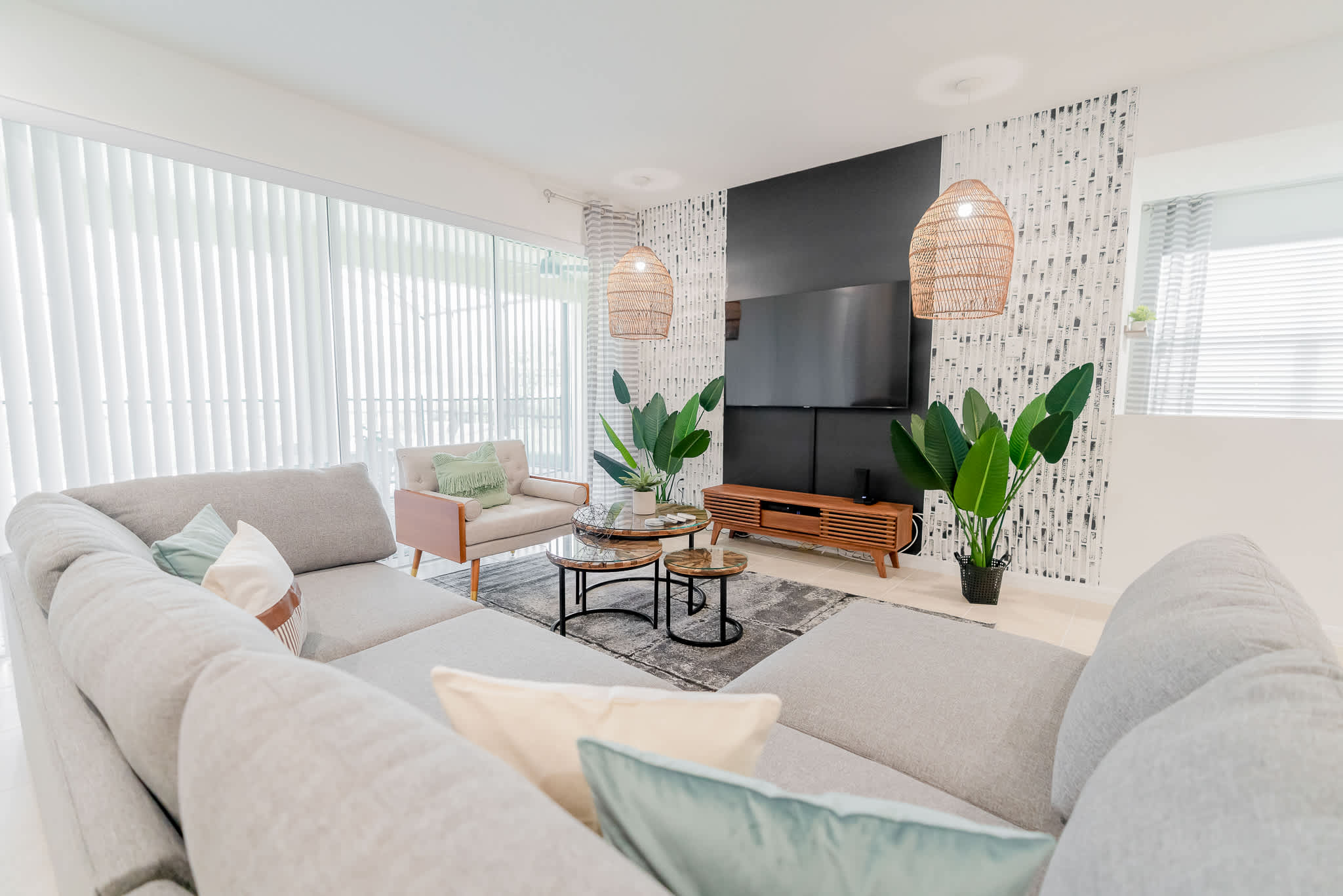 Relax in this stylish living room with modern decor, lush greenery, and a large TV for entertainment.