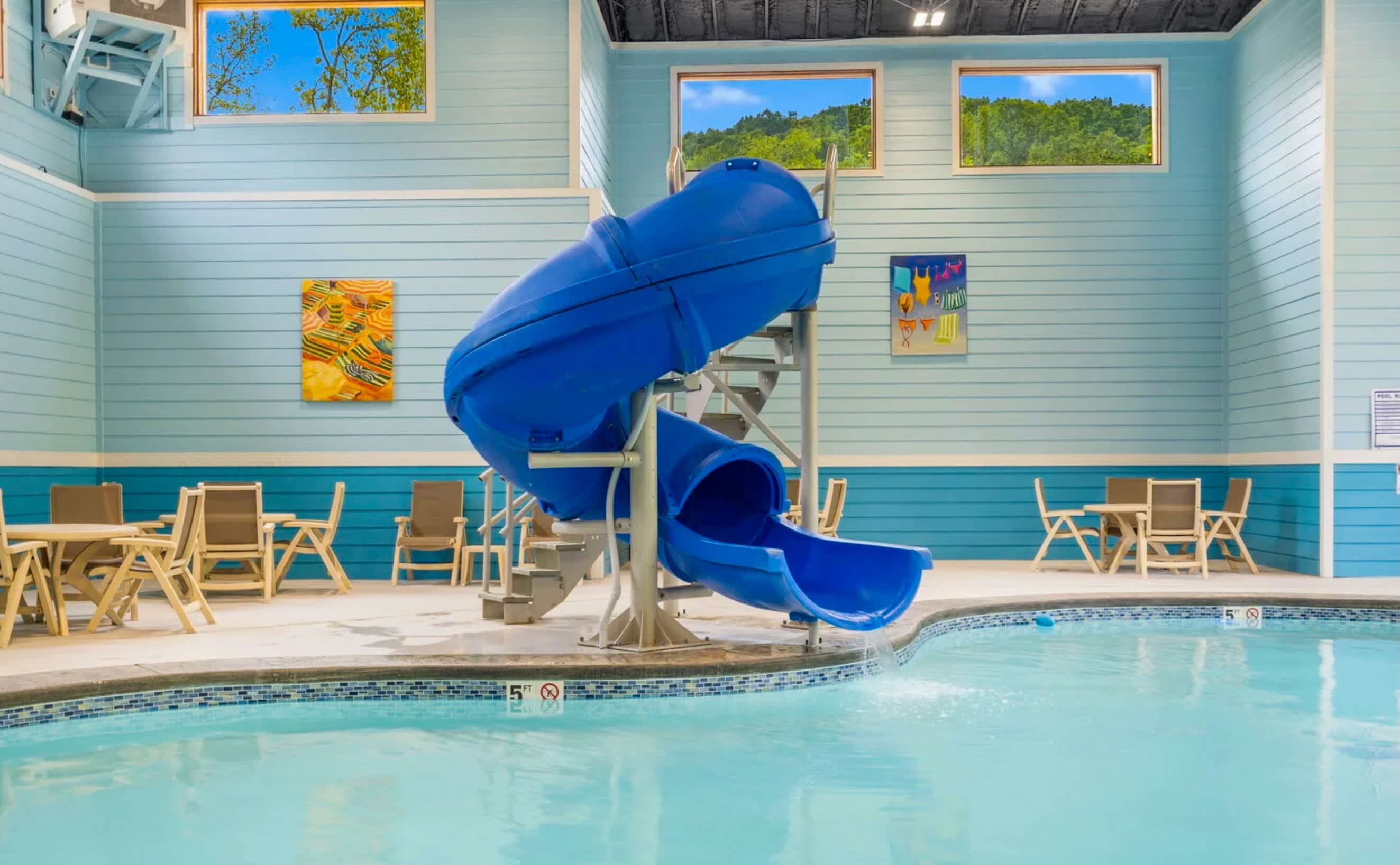 Stunning indoor pool with with slide, tables and chairs and community hot tub.