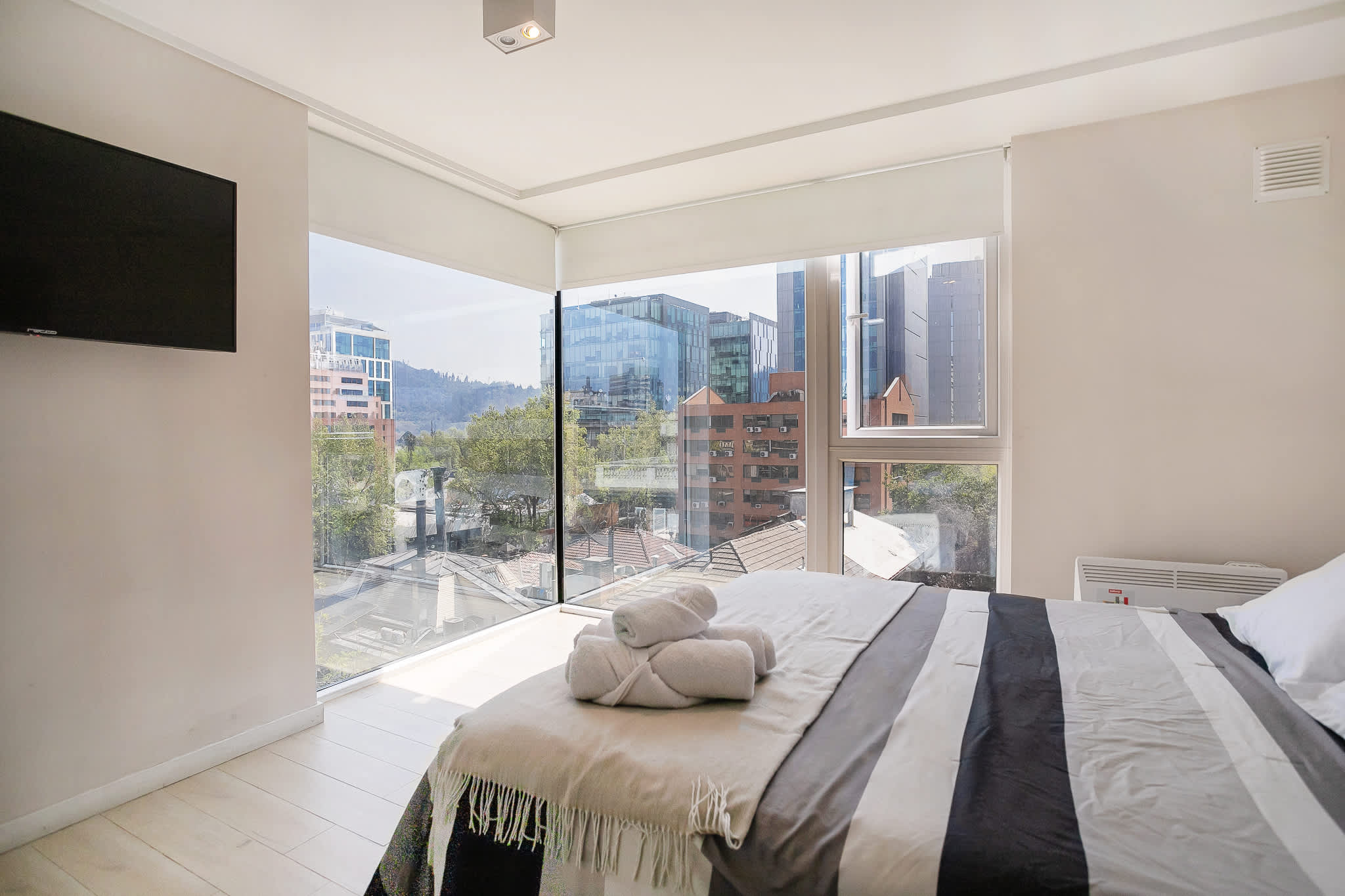Wake up to stunning city views in this bright and cozy bedroom, complete with a comfortable bed and modern amenities.