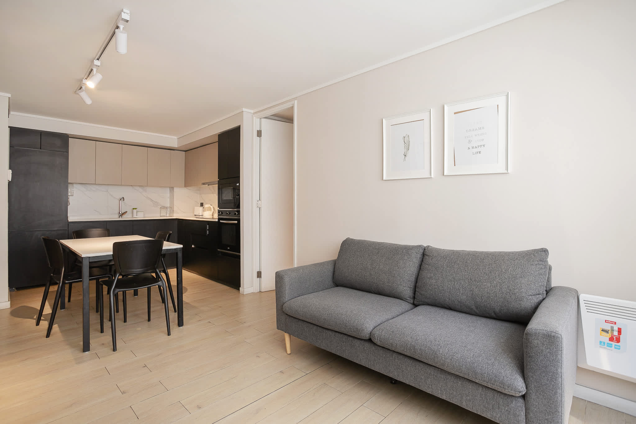 Enjoy a cozy and modern living space with a sleek kitchen and comfortable seating in this stylish apartment.
