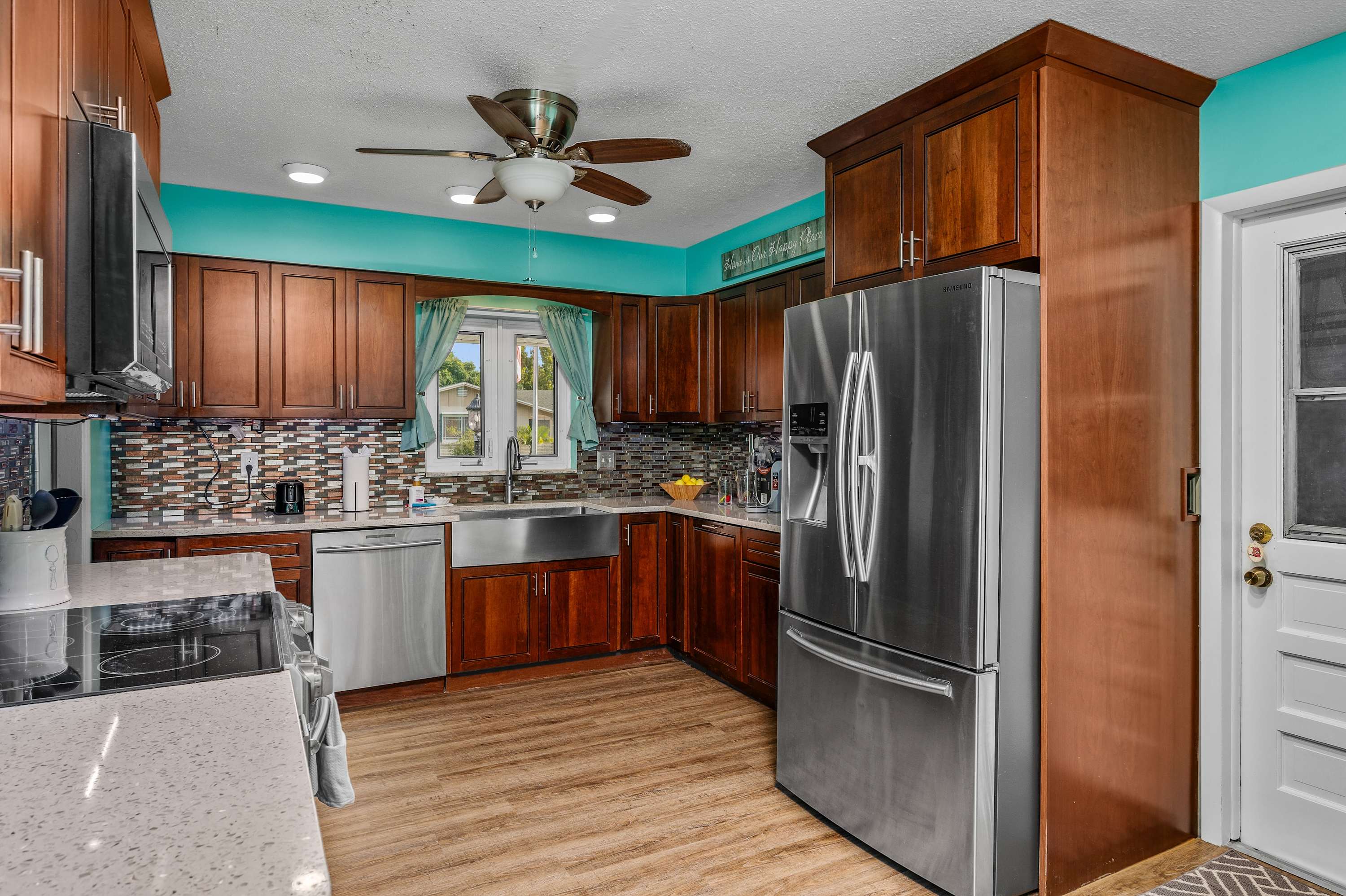 Prepare your favorite meals in this charming and fully equipped kitchen, featuring wood cabinetry, modern stainless steel appliances, and a unique teal backsplash that adds a pop of coastal color.