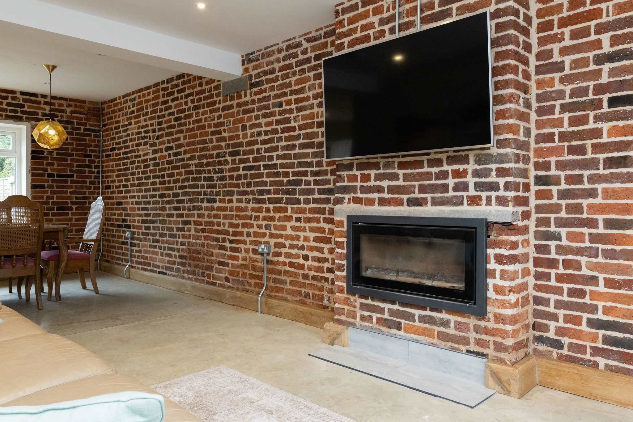 The feature brick wall with its mounted TV and fireplace creates a warm and inviting space to relax with family in the evenings.