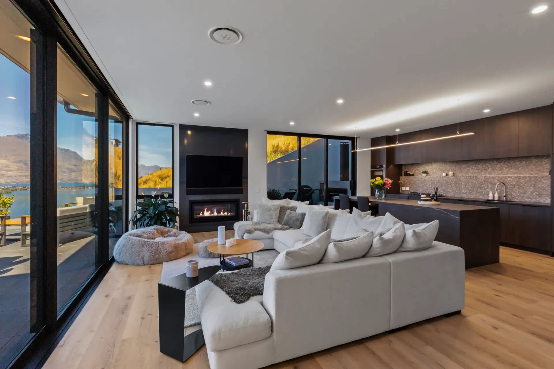 Modern open-plan lounge with fireplace and mountain backdrop
