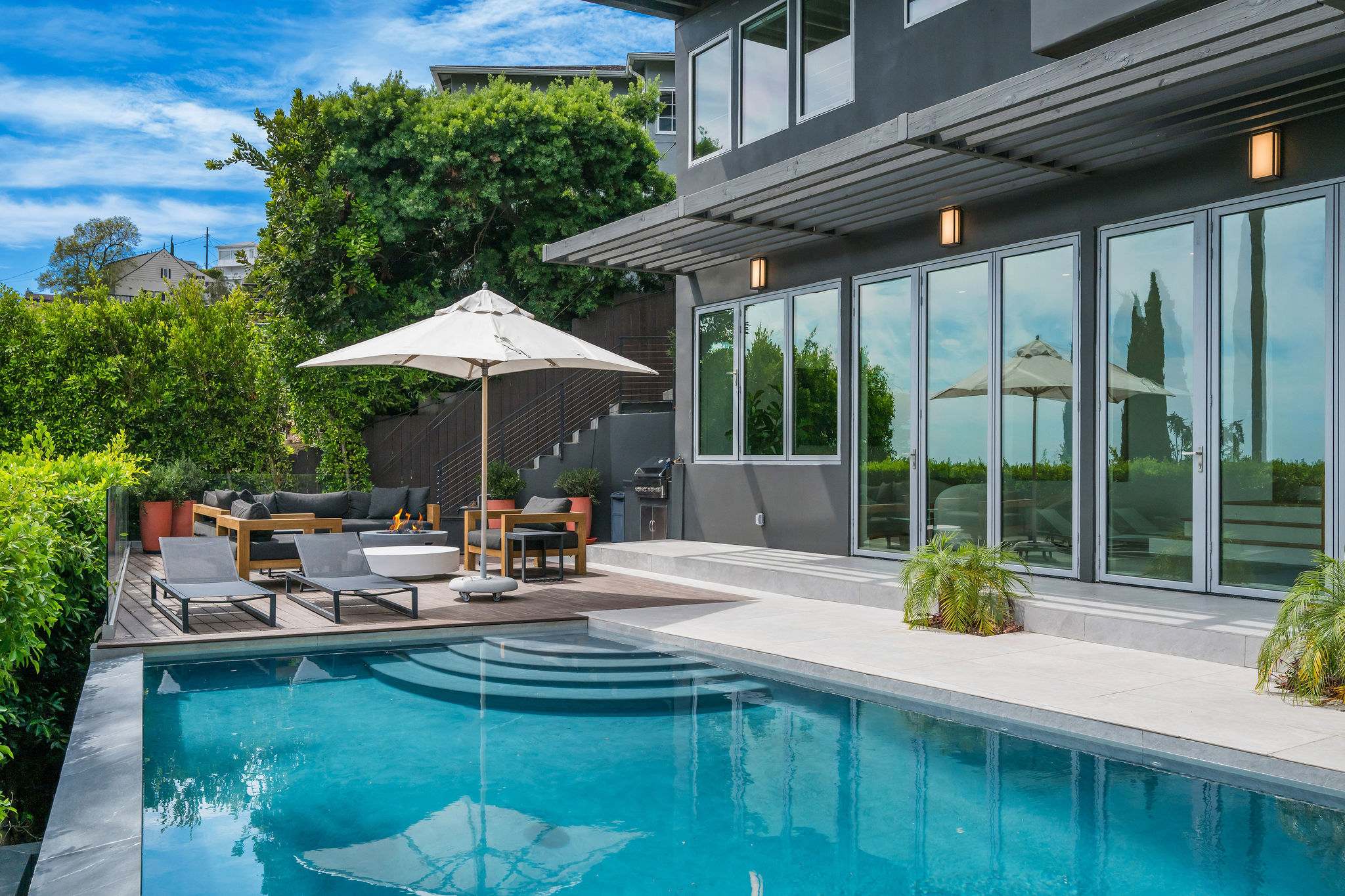 Outdoor area with pool, outdoor seating, indoor-outdoor fun room connecting the pool to the inside of the home