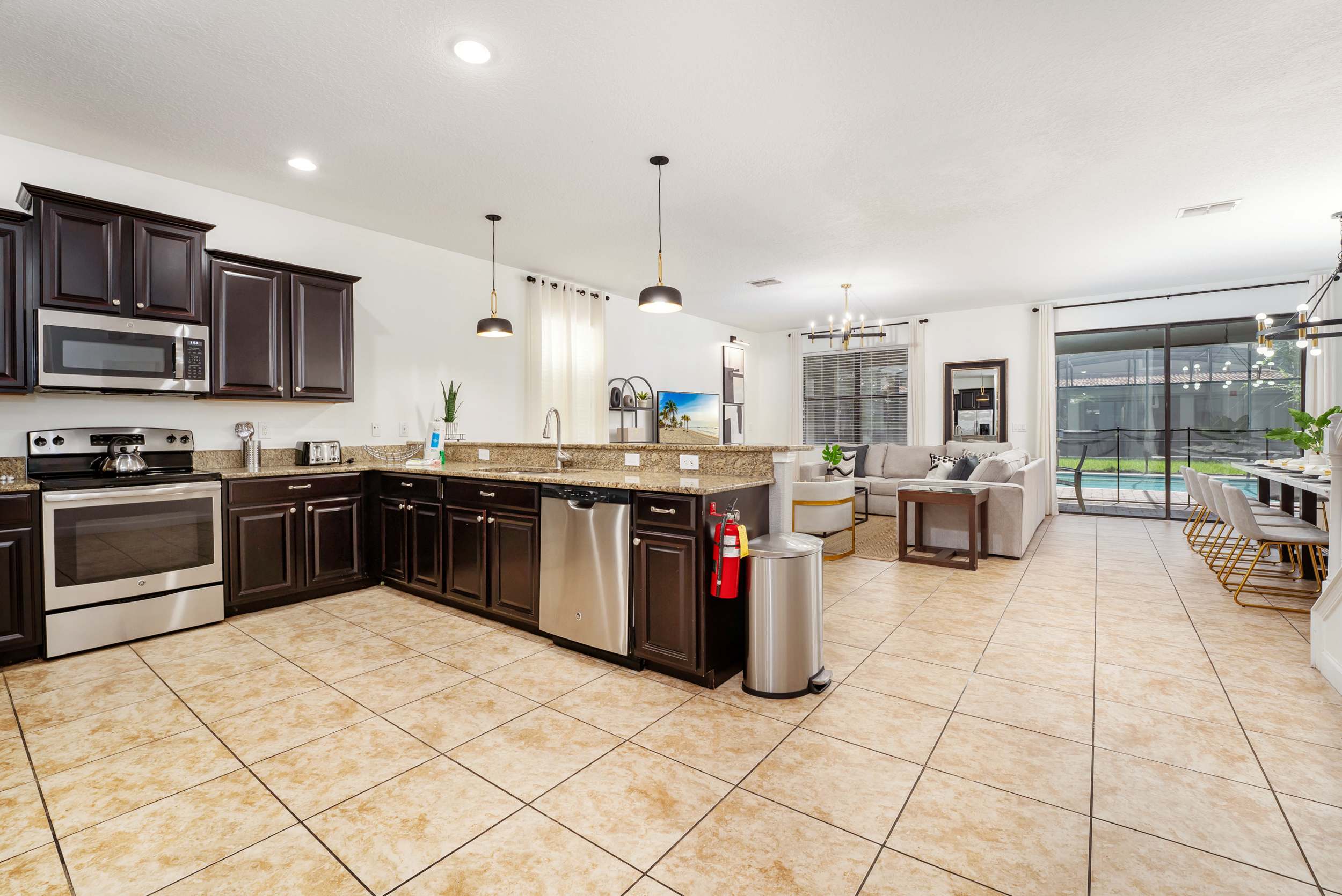 Open-concept kitchen with granite counters, stainless-steel appliances, and a dining area overlooking the screened pool patio.