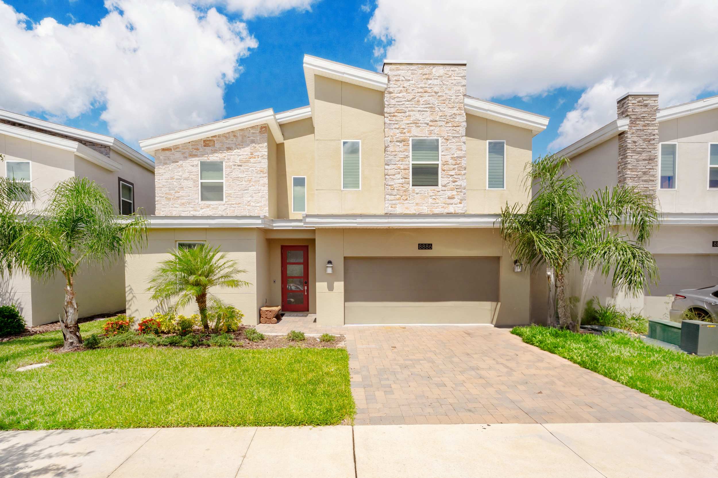 Experience luxury in this stunning villa with a modern stone facade and lush landscaping, perfect for your next getaway.