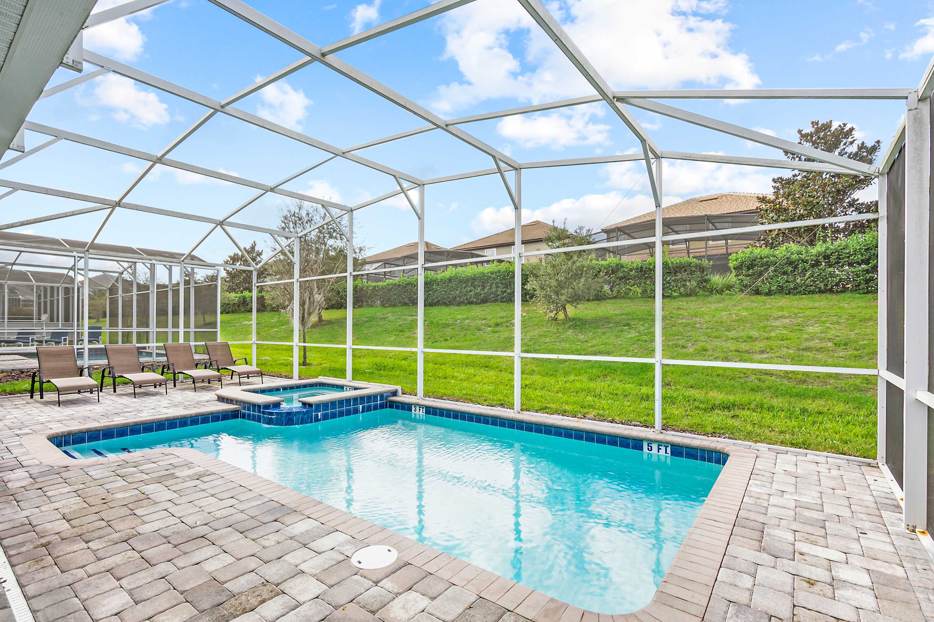 Private screened pool with an attached hot tub, cushioned loungers, and a sunny green outlook—an inviting outdoor retreat for relaxing together.