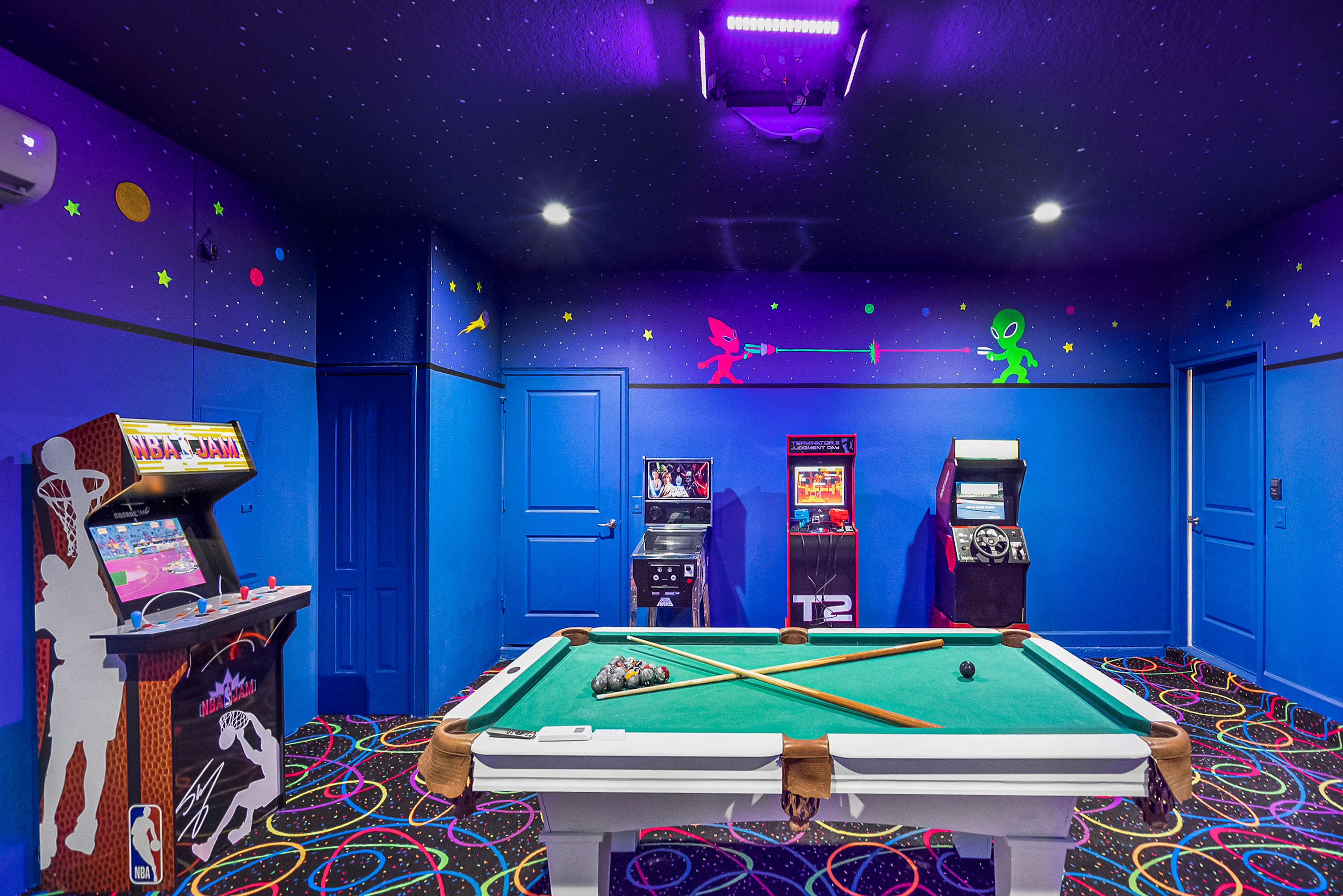 Experience out-of-this-world fun in this cosmic game room with a pool table and classic arcade games for endless entertainment.