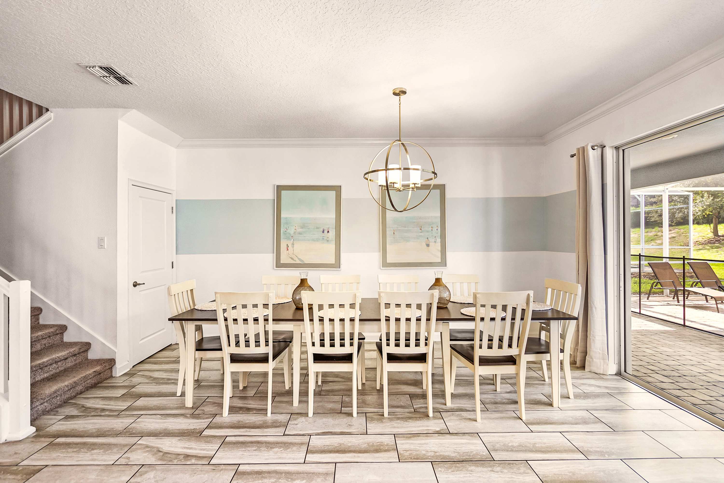Private dining room with seating for 10, coastal artwork, and sliding glass doors opening to a sunny patio.