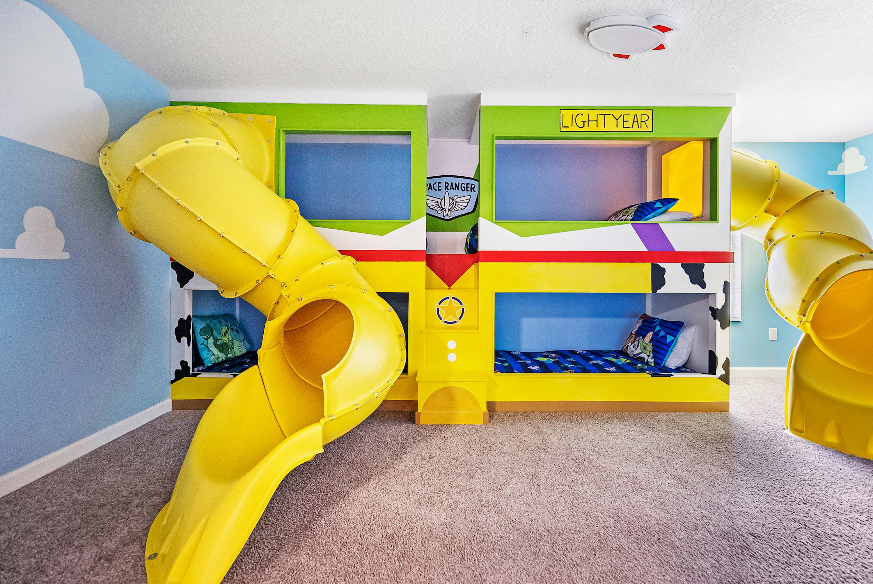 Experience out-of-this-world fun in this vibrant space-themed room with bunk beds and thrilling slides, perfect for an unforgettable family adventure.