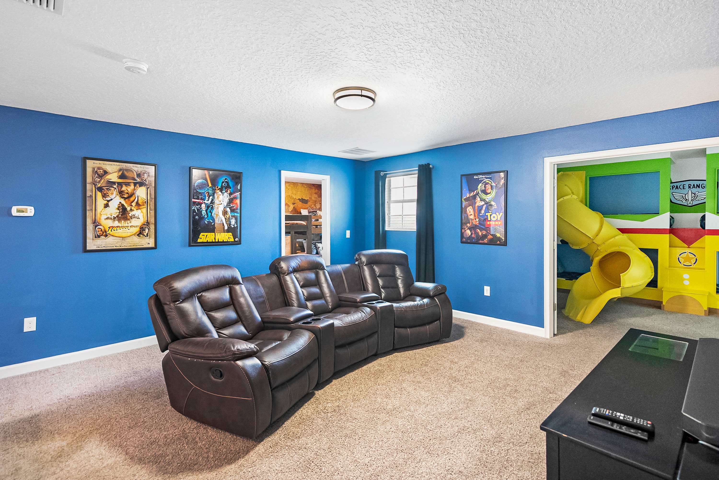 Enjoy movie nights in plush recliners and let kids explore the vibrant play area with a slide for endless fun.