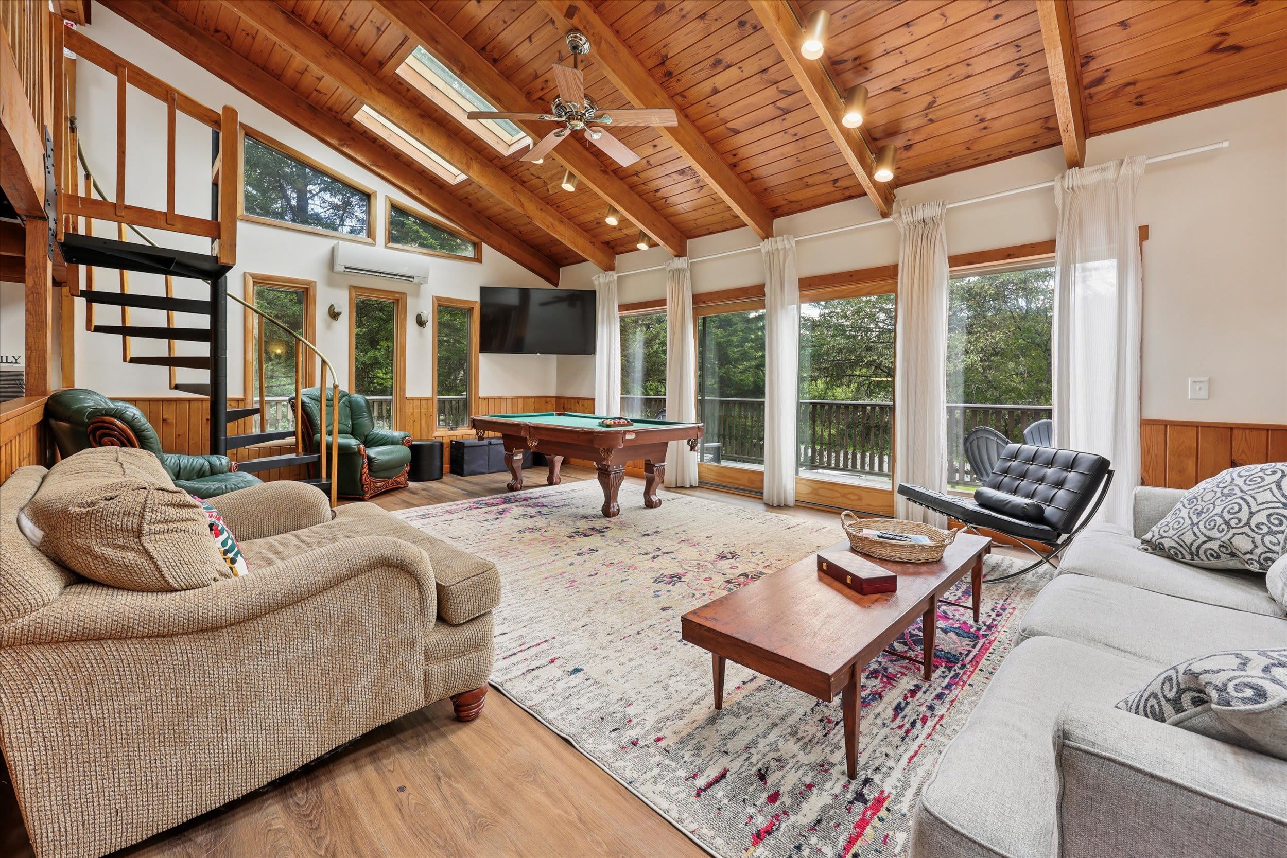 Gather in the sun-filled living room with soaring wood ceilings, skylights, and a pool table nearby.