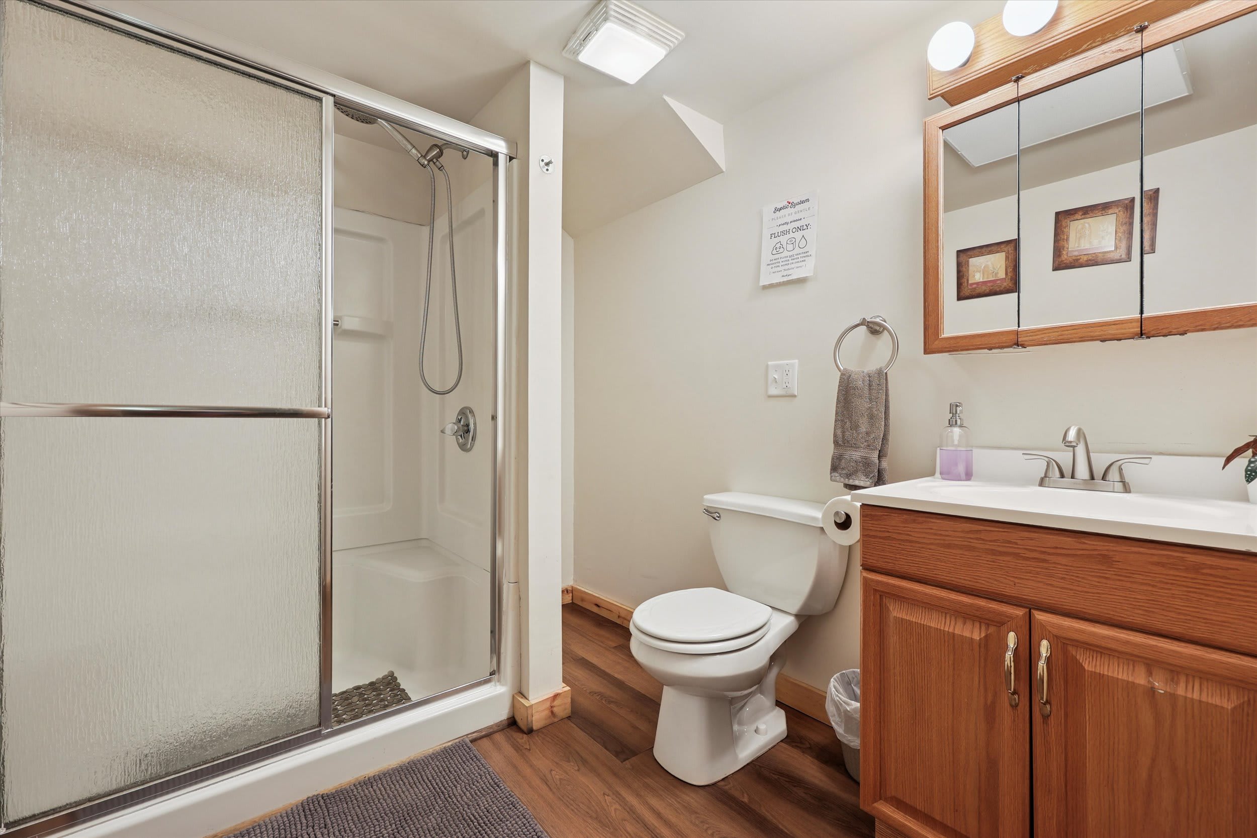 A full bathroom with walk-in shower, skylight, and wood-finished vanity for your comfort.
