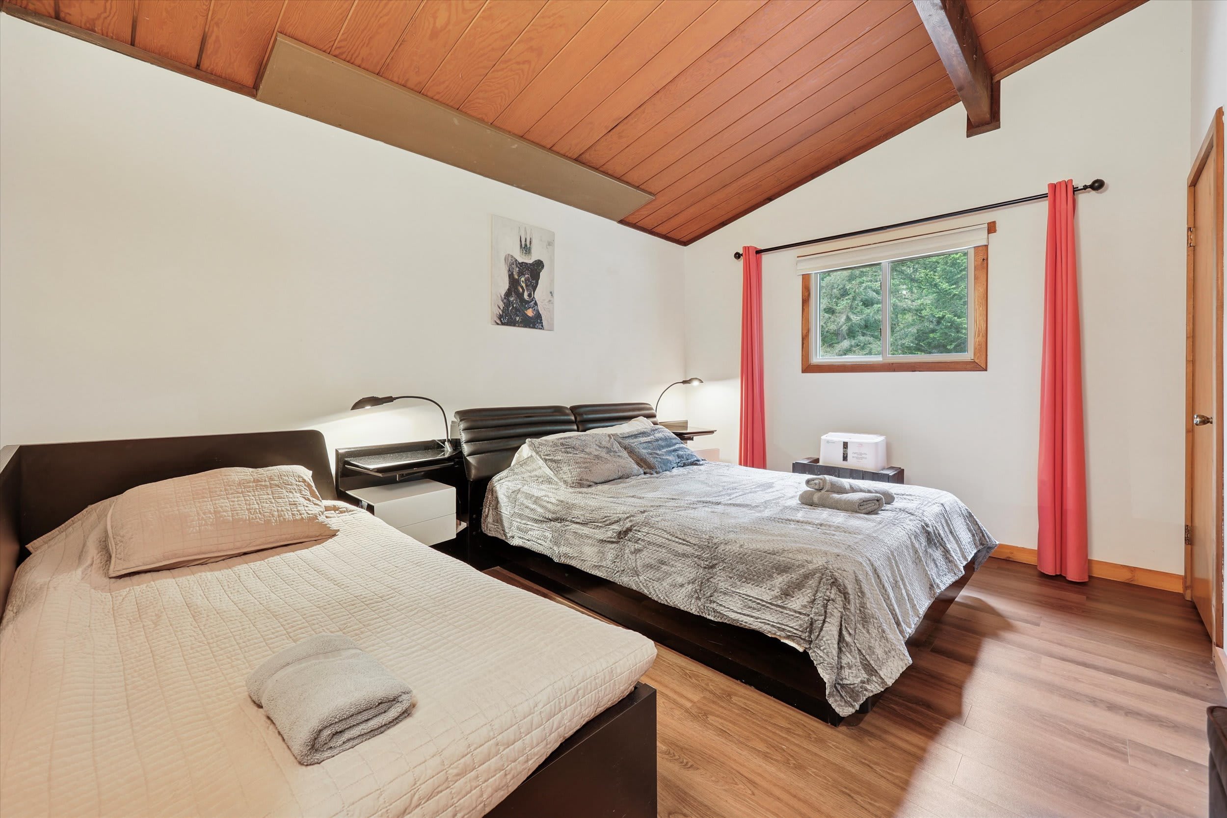 Another view of the bedroom showing tree-framed windows and cozy bedding for a restful night.