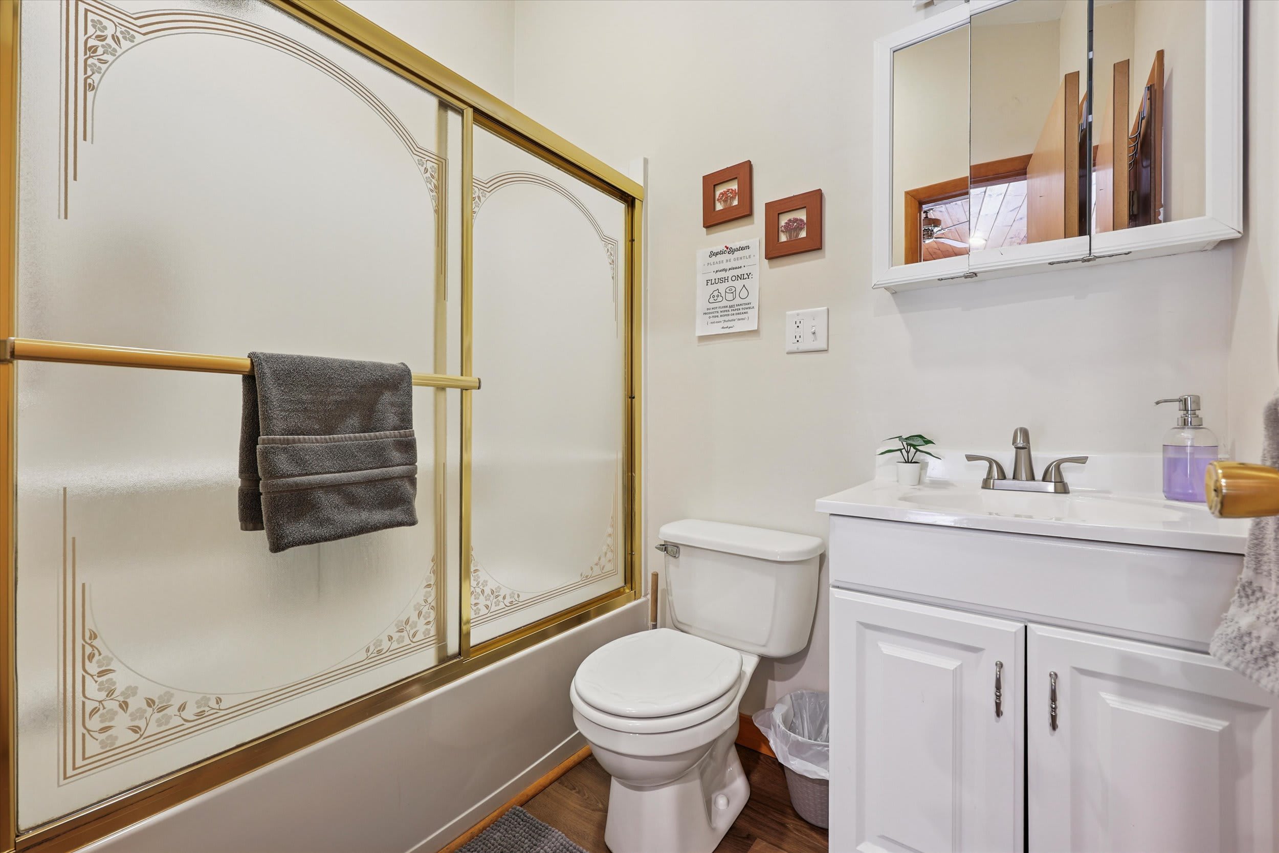 This full bathroom features a tub-shower combo with elegant glass doors for added convenience.